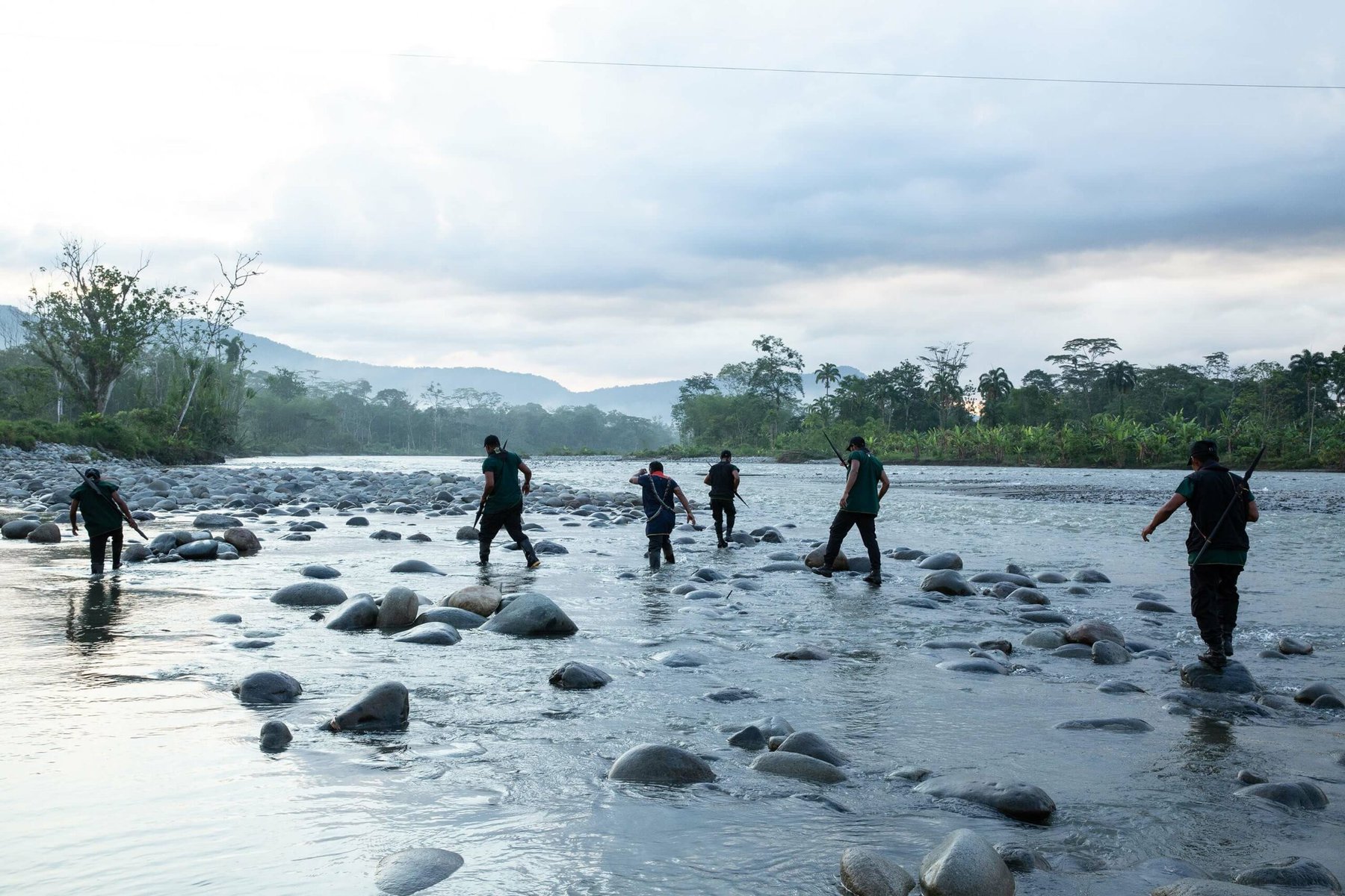 Indigenous guards walk across the Aguarico River.