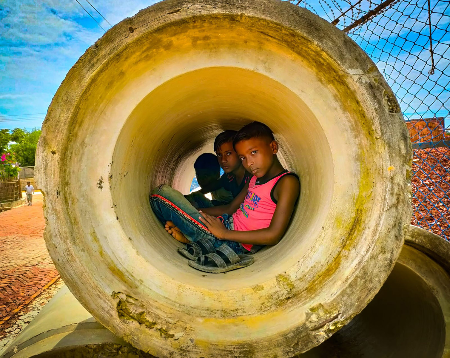 Children resting inside a large cement pipe. 