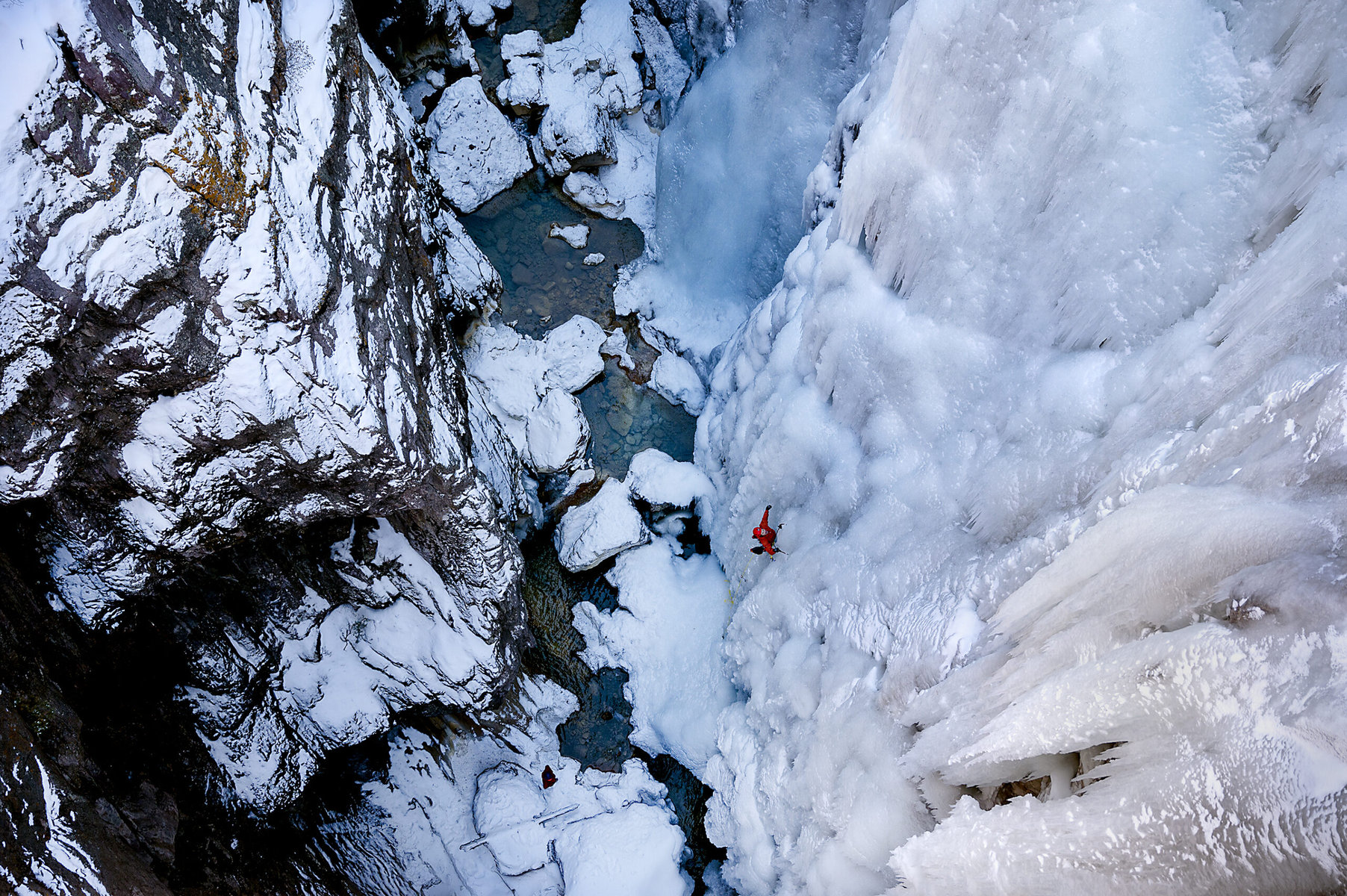 A climber at the Ouray Ice park with a deep ravine below.