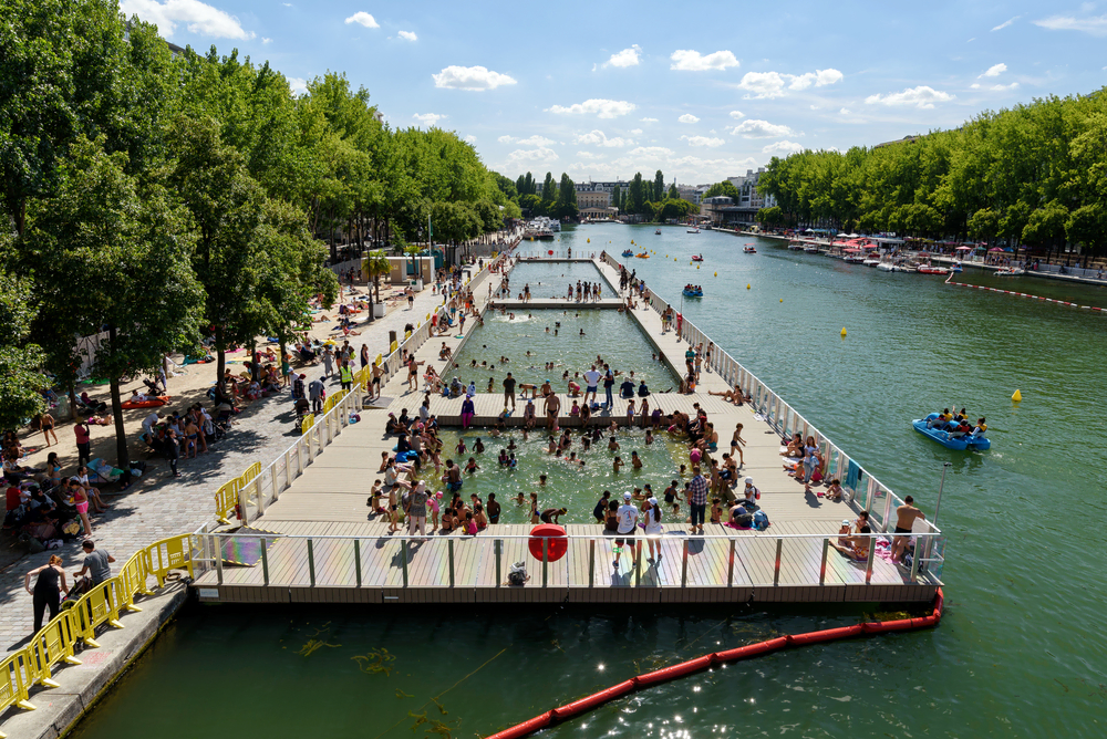Pools along a canal in Paris are crowded with swimmers.