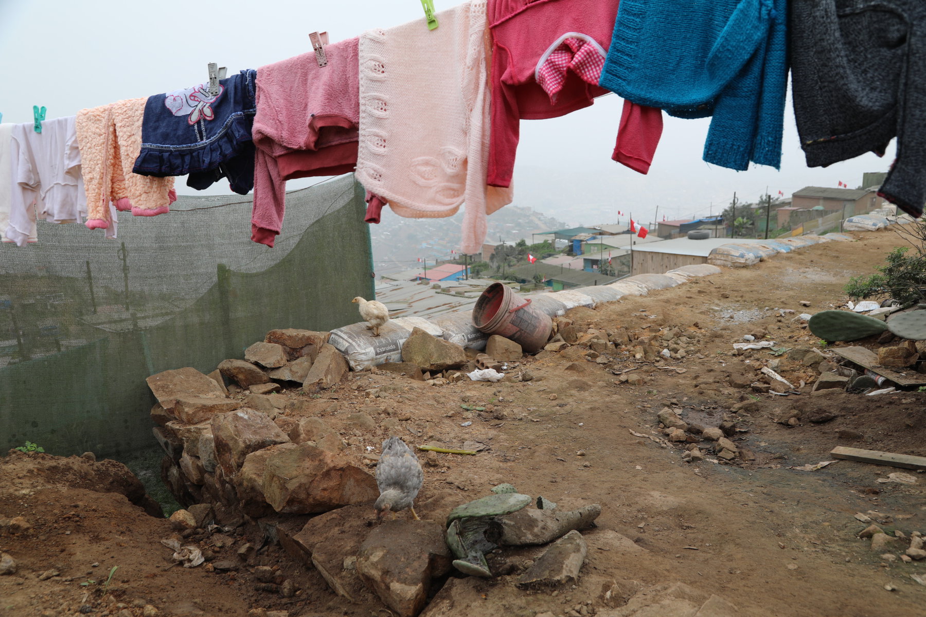 Clothes hang on a line with fog catchers in the background.