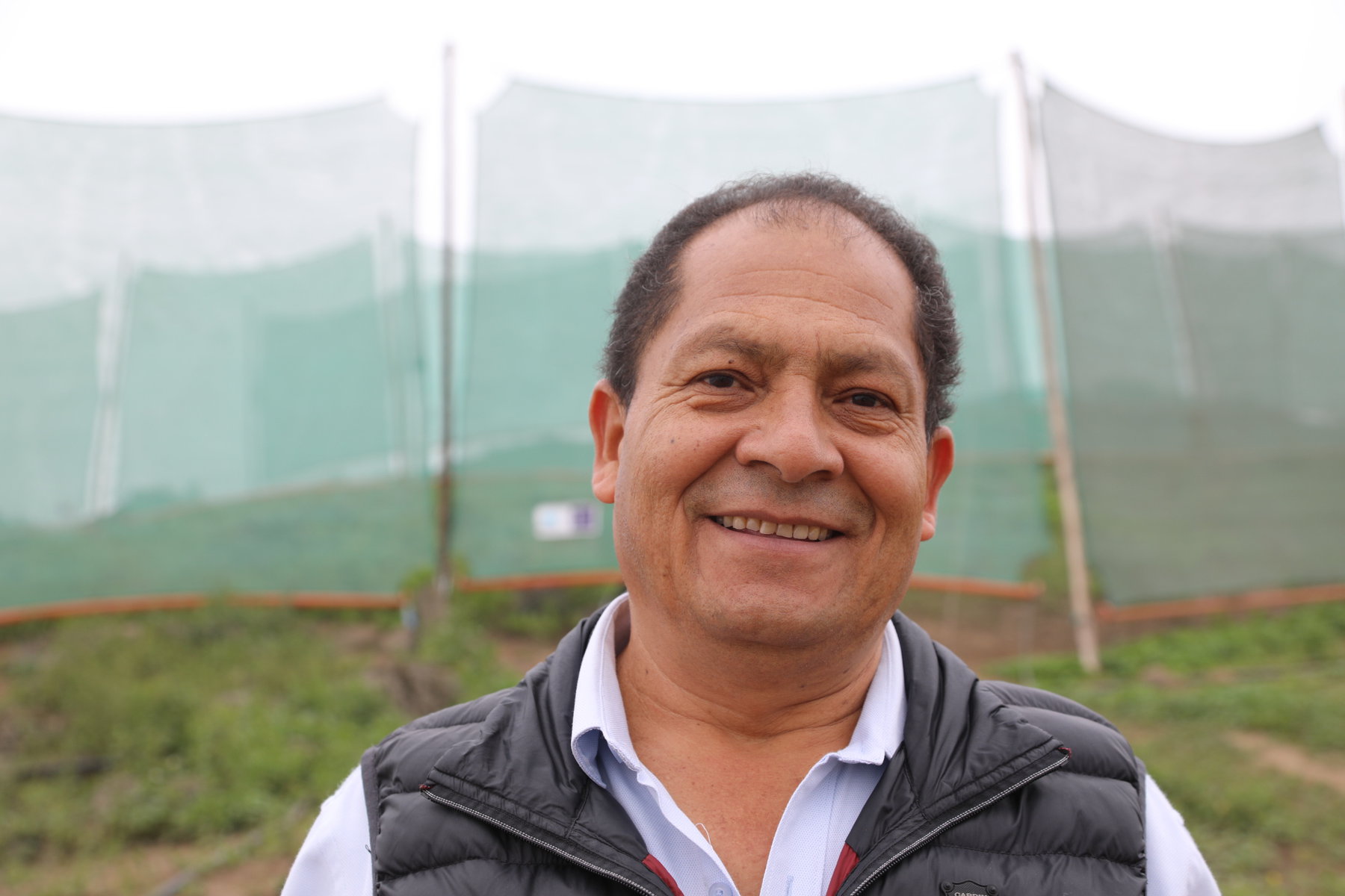 Abel Cruz in front of a row of mesh fog catchers. 