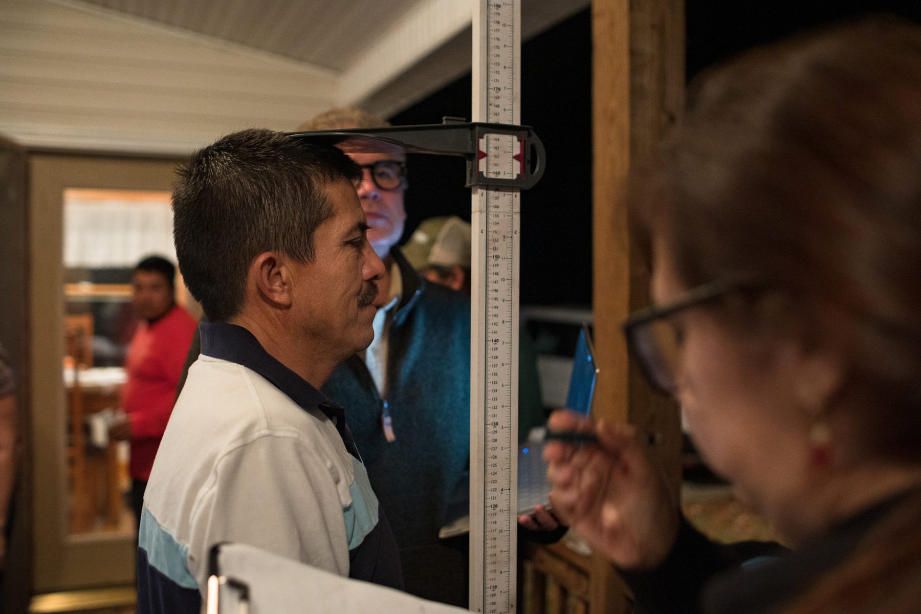A farmworker has his height taken during a Vecinos mobile medical clinic farm visit.