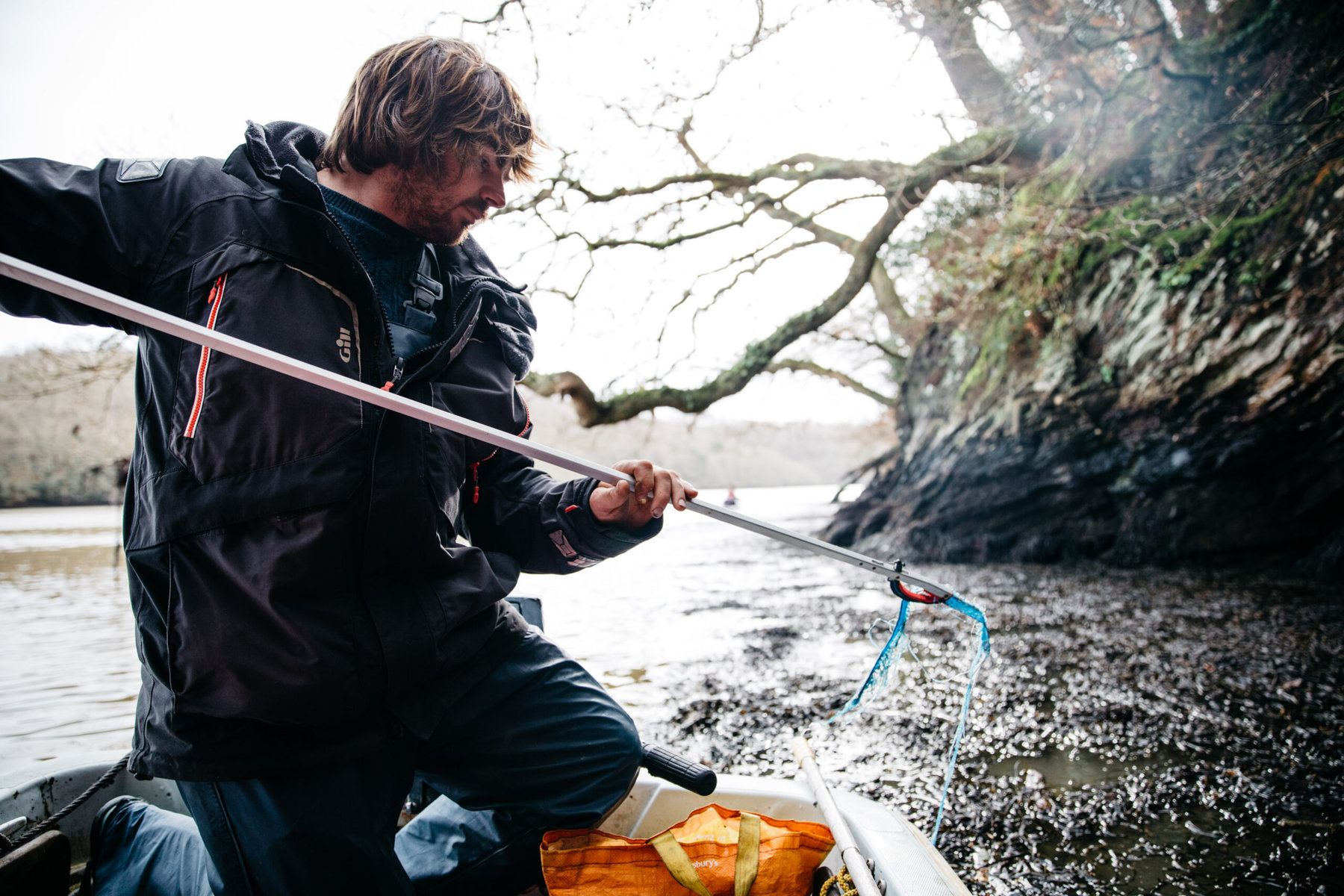 Green picks up plastic from a river bank