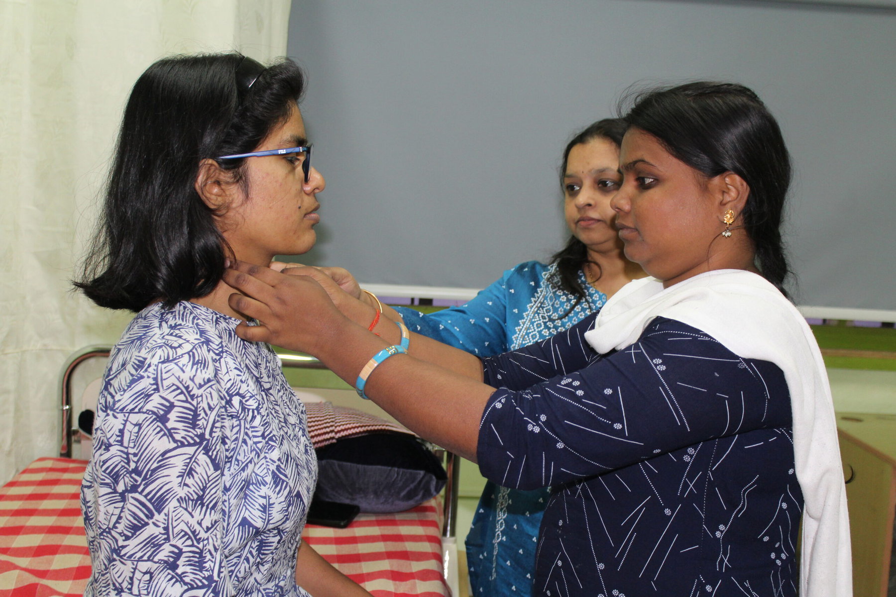 Aishwarya Amalapuram practices on co-trainee Ritika Maurya (sitting), with Ashwini the trainer behind her.