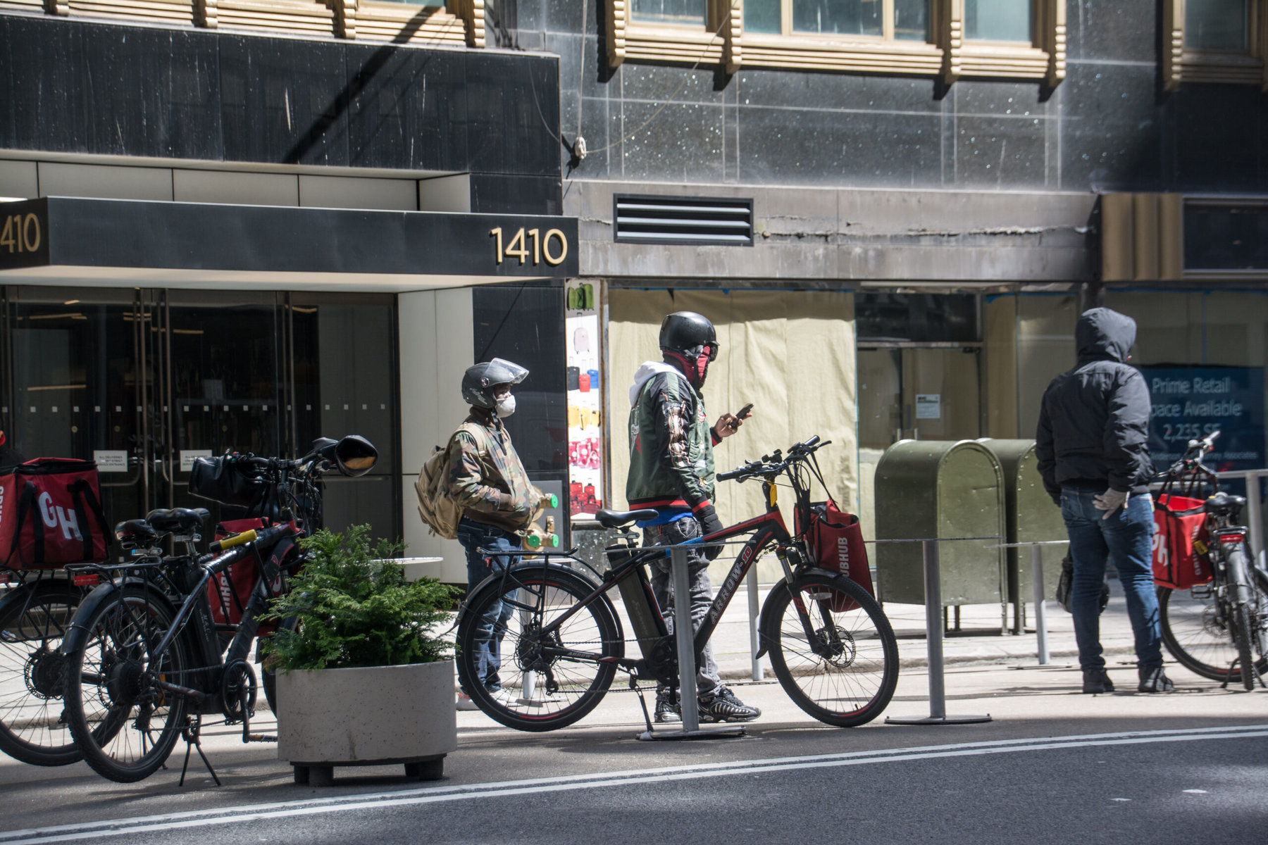 Delivery workers wait outside a restaurant to pick up orders.