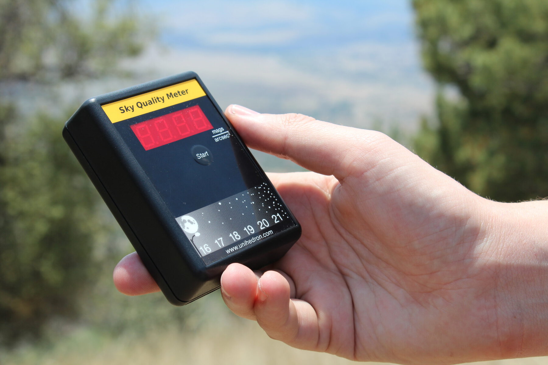 A hand holds a sky quality meter