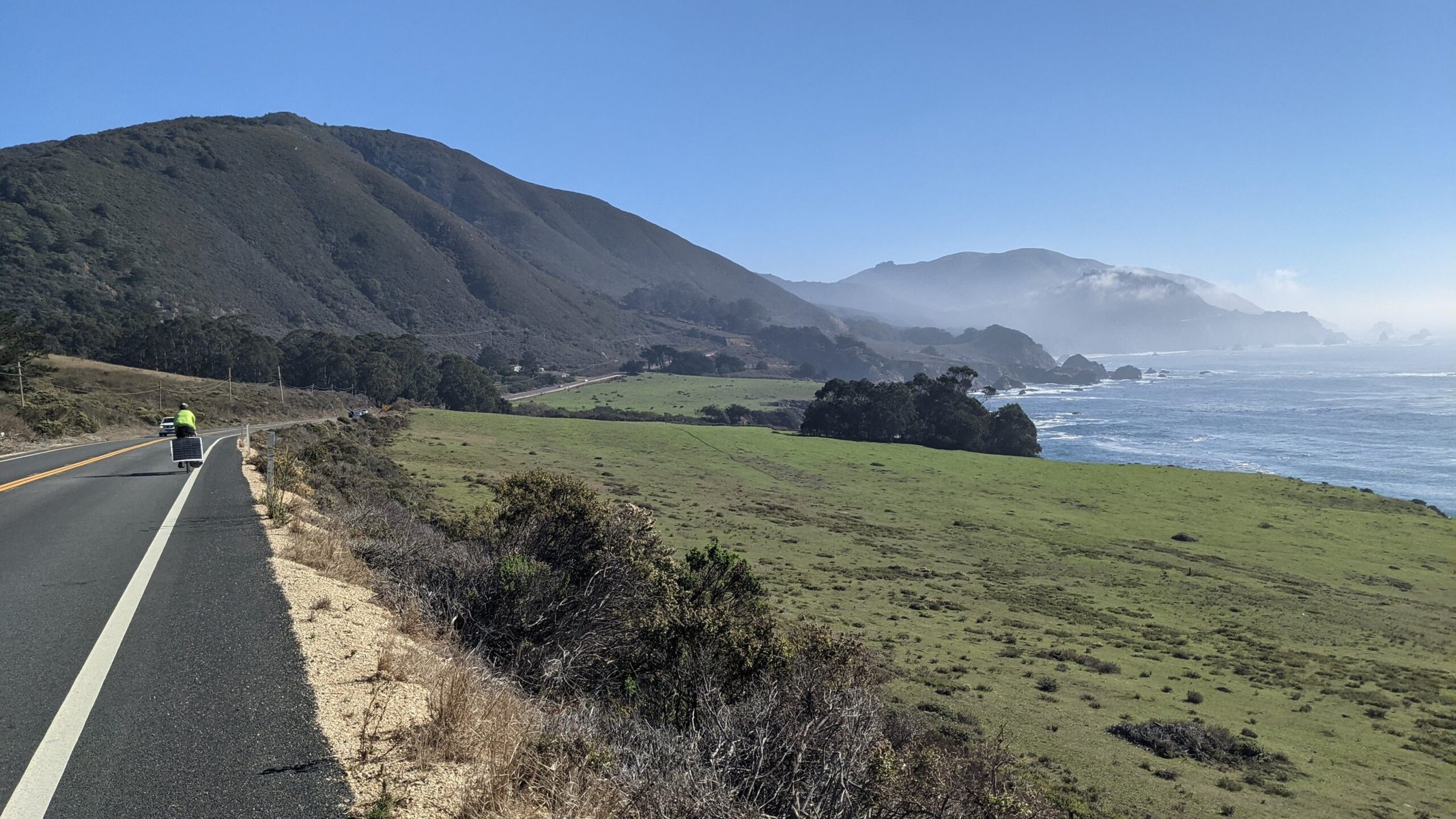 A cyclist on a road along the coast.