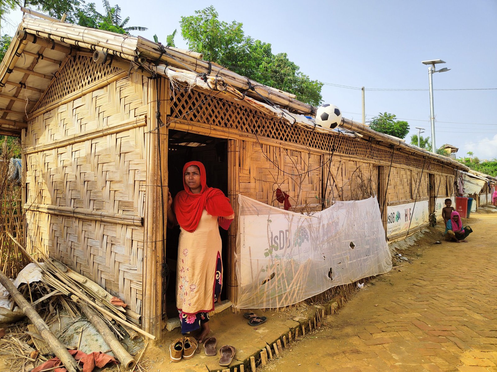 A Rohingya woman stands at the door of the shelter that she was provided after her old shelter was affected by a landslide in another camp.
