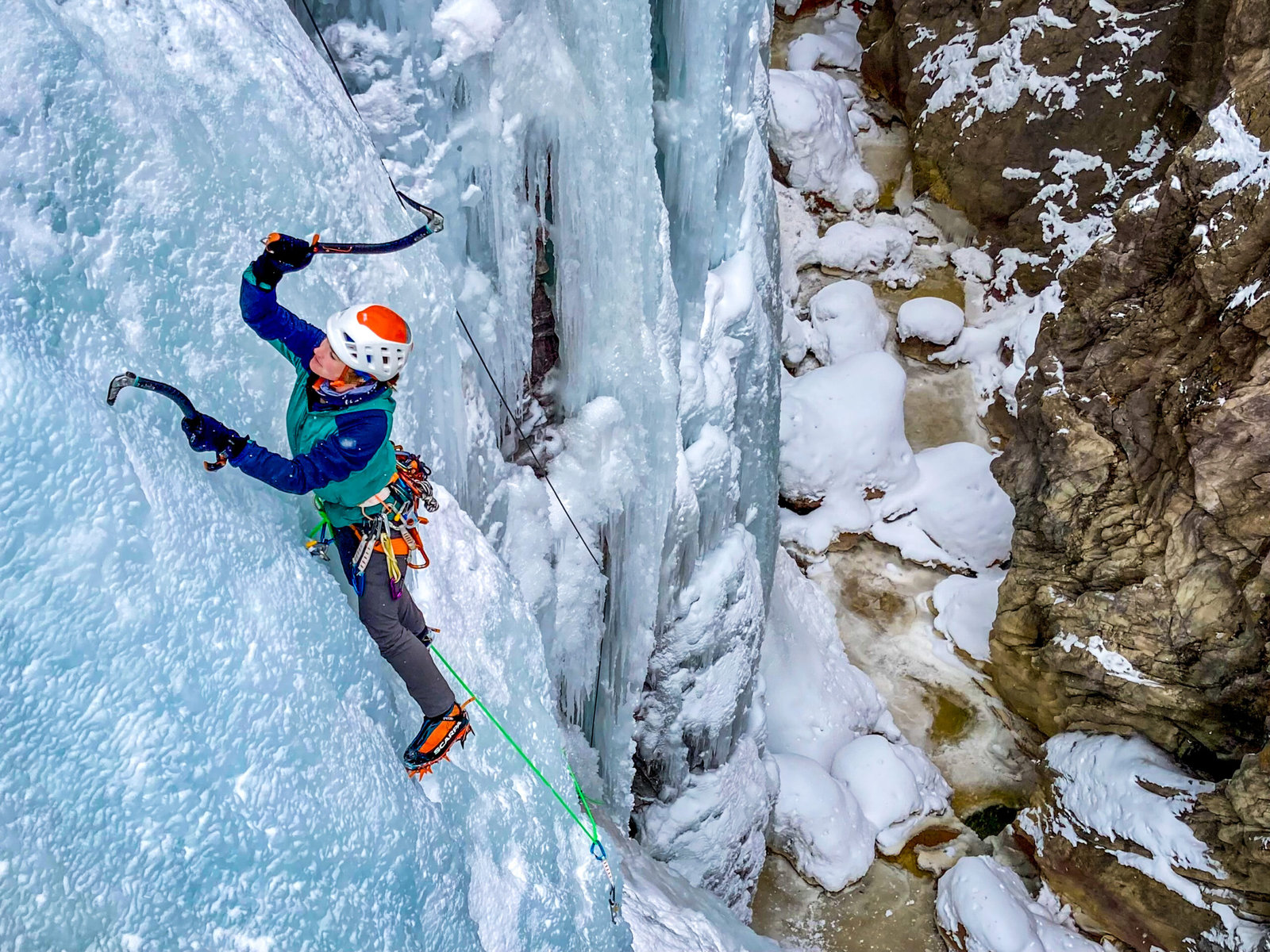 A climber at the Ouray Ice Park with a deep ravine below.