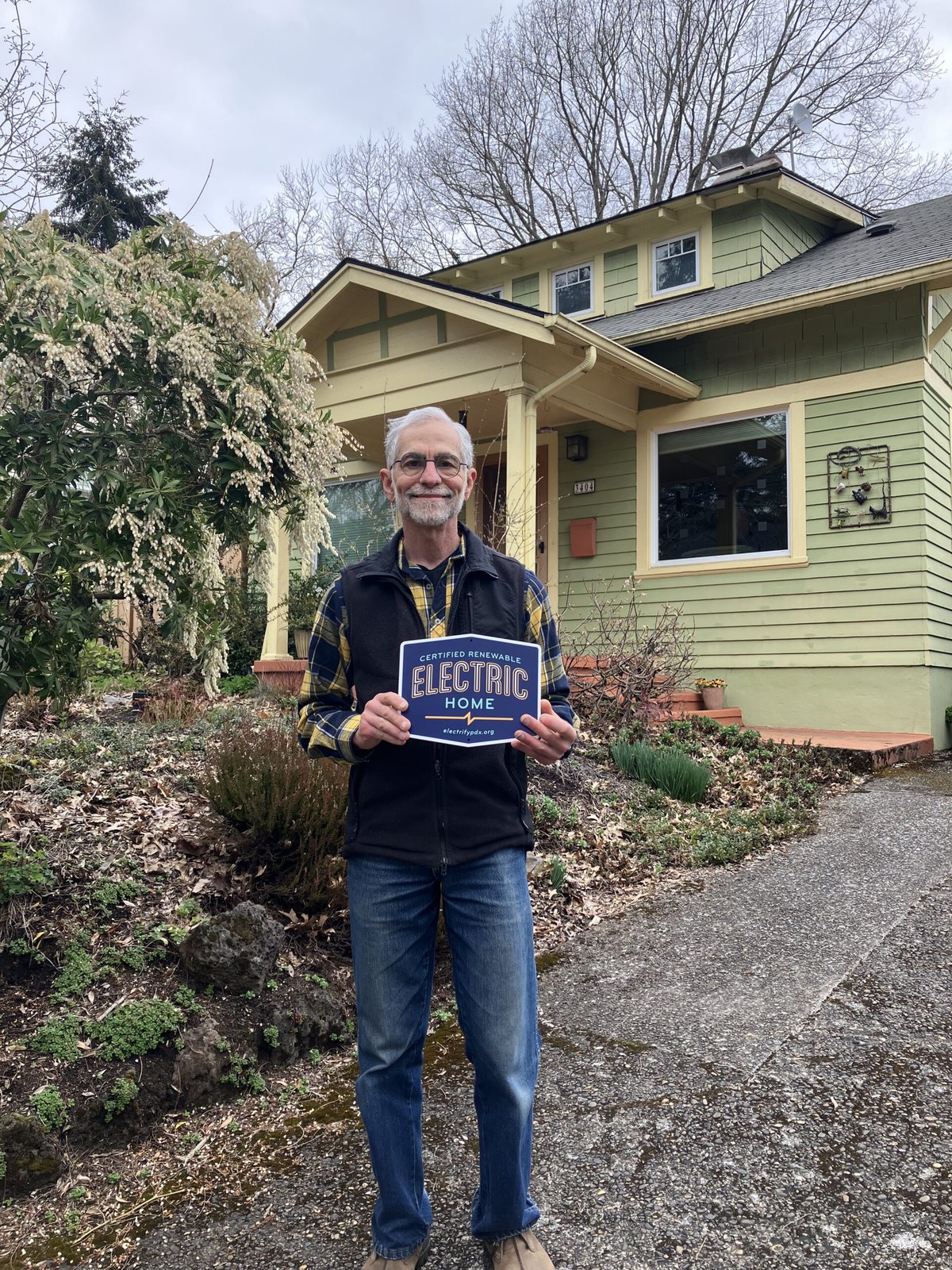 An ElectrifyPDX participant, Jerry, holds up his certification in front of his home. 