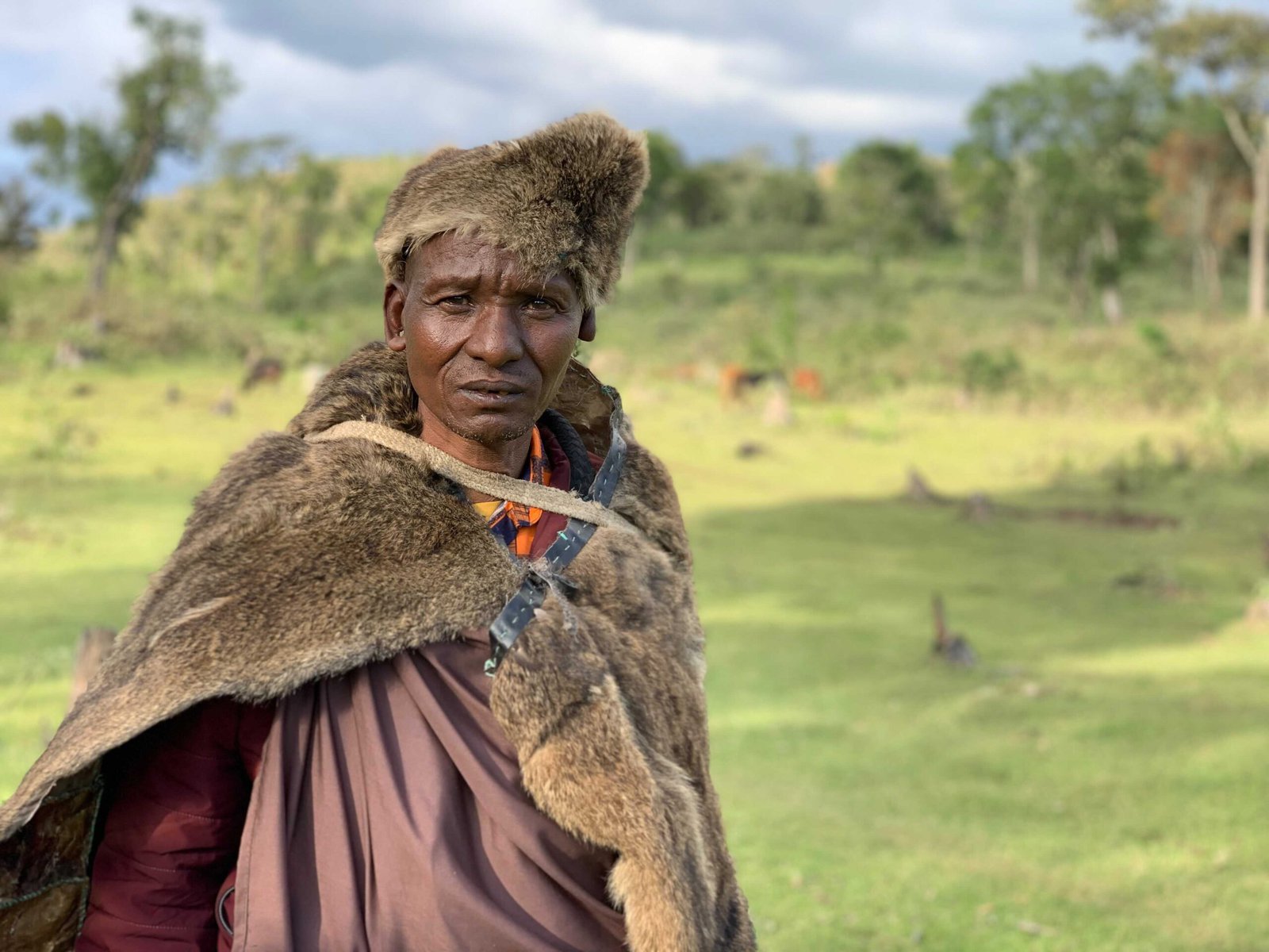 Samuel Salaton, a member of the Ogiek community, stands on land right next to Mau Forest. He is dressed in furs.