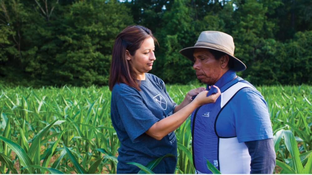 Roxana Chicas outfits a farmworker with a device.