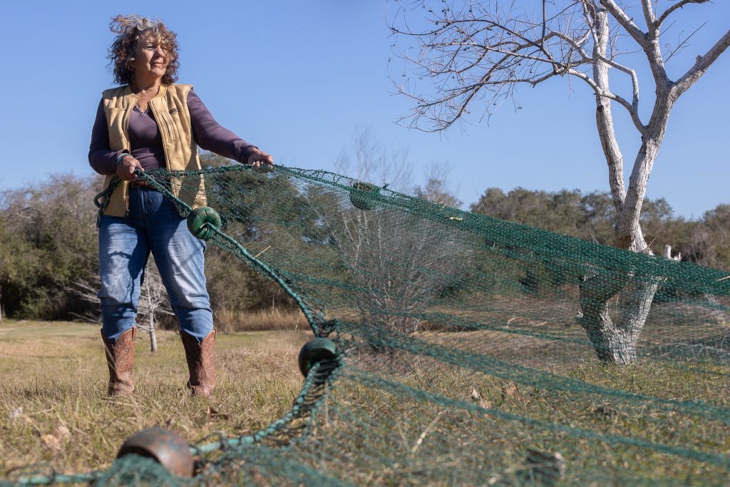 Diane Wilson untangles green shrimp netting.