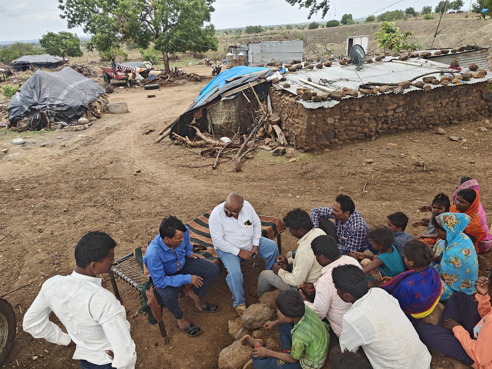 Tangde and Kamble talk with a group of people in a rural village.