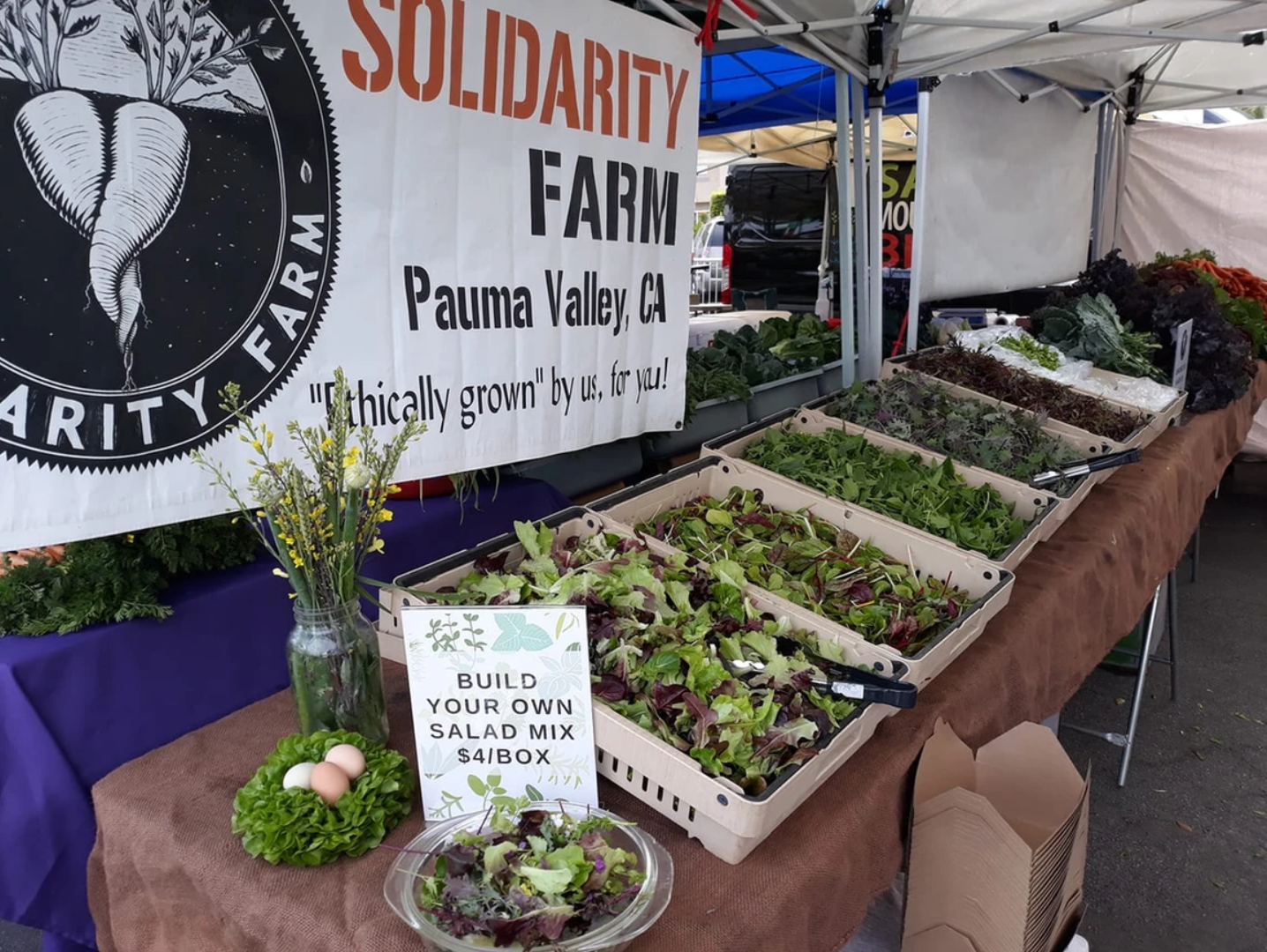 A farmers market booth full of salad greens.