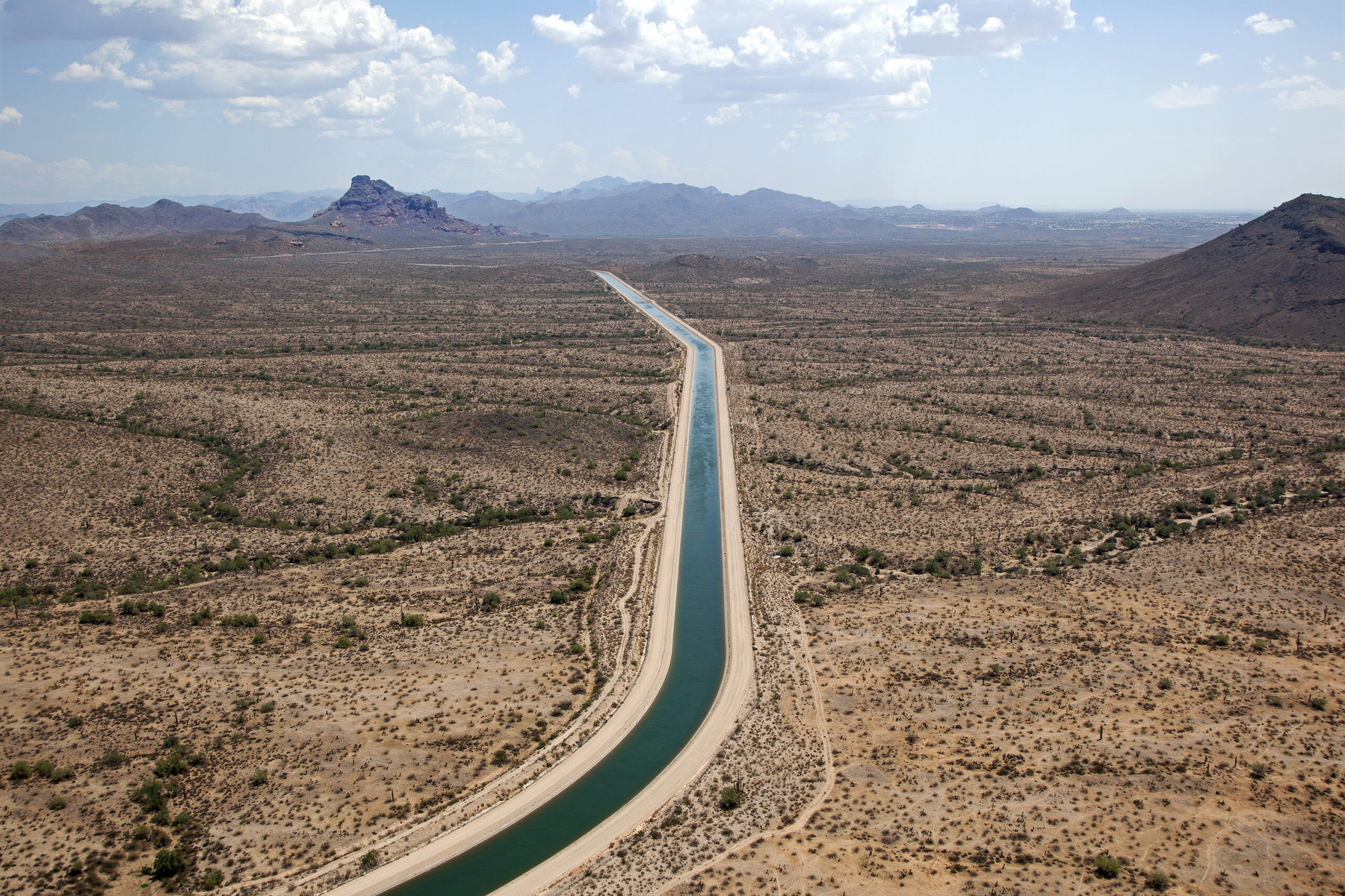 A view of the Central Arizona Project carrying water through the Arizona desert with mountains in the background.