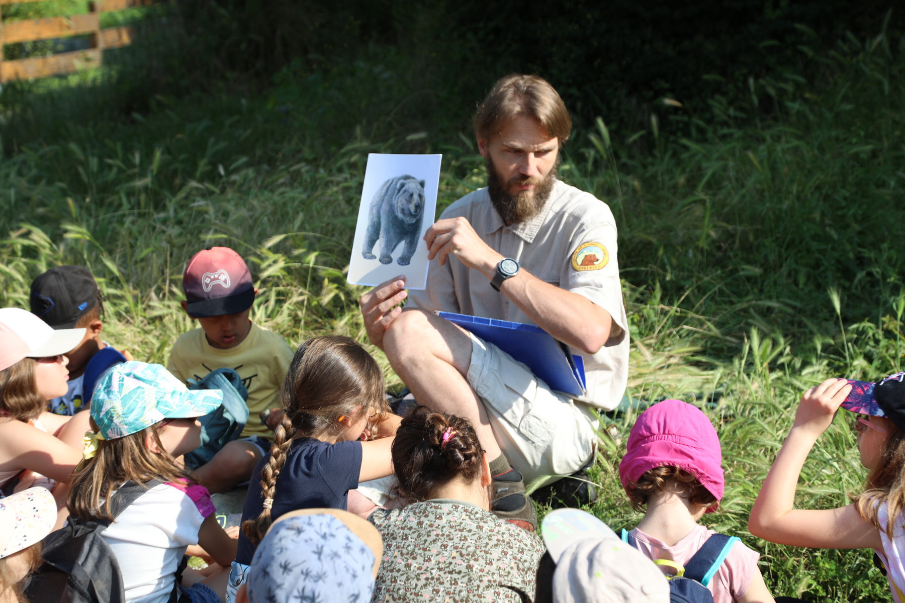 A mountain guide holds up a picture of a bear for a group of school kids.