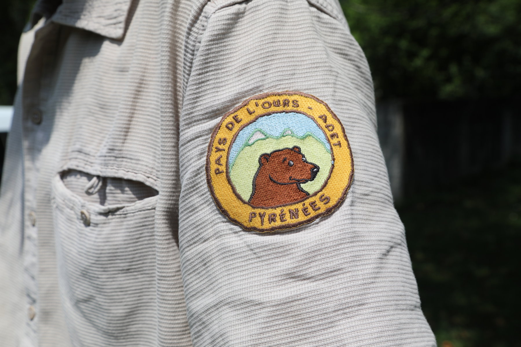 A Pays de l'Ours patch on a shirt.