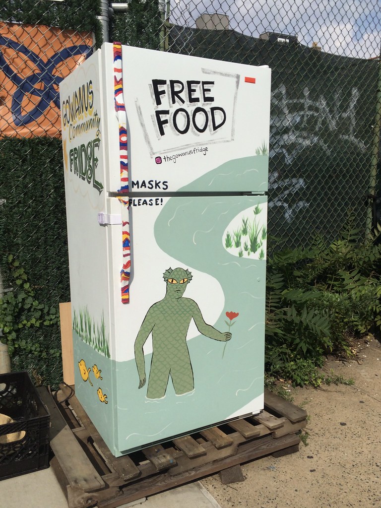 A community fridge in Gowanus, Brooklyn. It is painted with a monster offering a flower. 