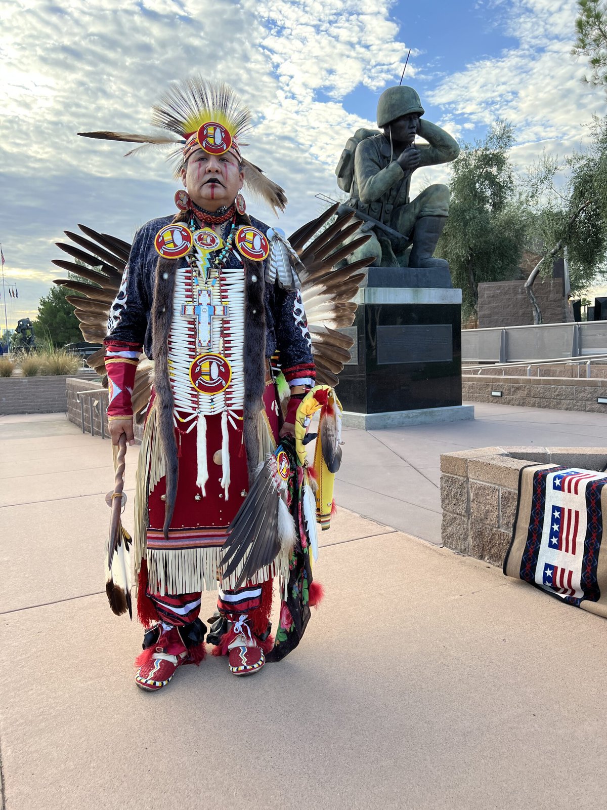 Dressed in his traditional dance regalia, Allen King stands before the Navajo Code Talker statue in downtown Phoenix. 