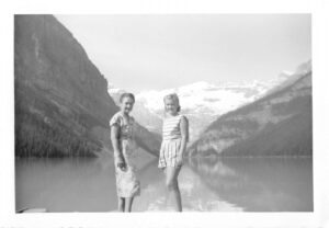 Two people pose in front of a lake in a black and white photo.