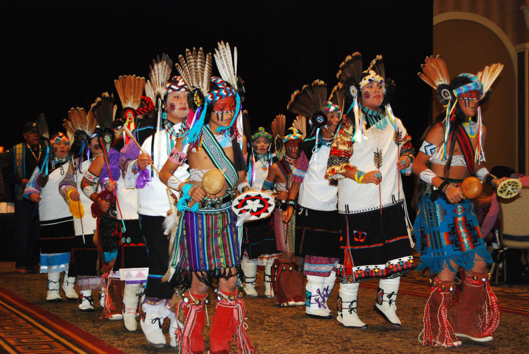 Wearing headdresses adorned with red-tailed hawk and turkey feathers, Hopi children perform a Komantsi katsina dance, which honors Comanche warriors.