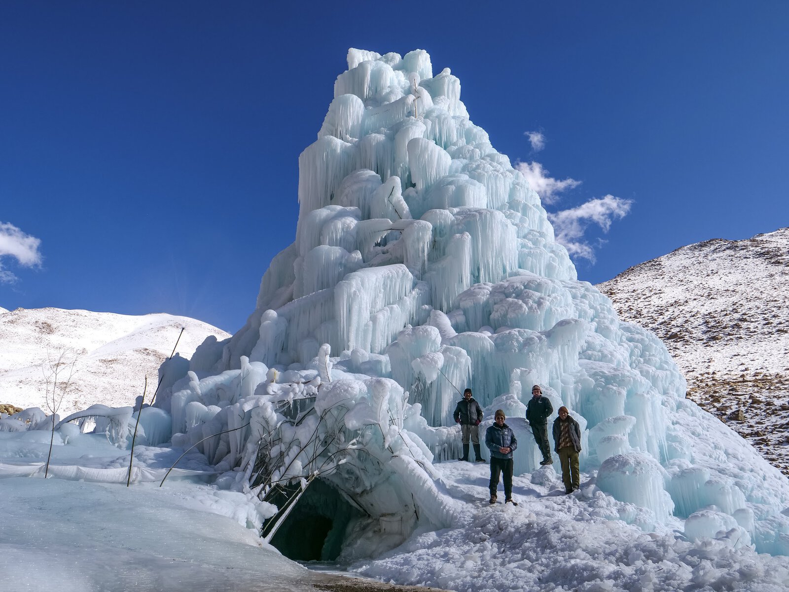People stand in front if an ice stupa.