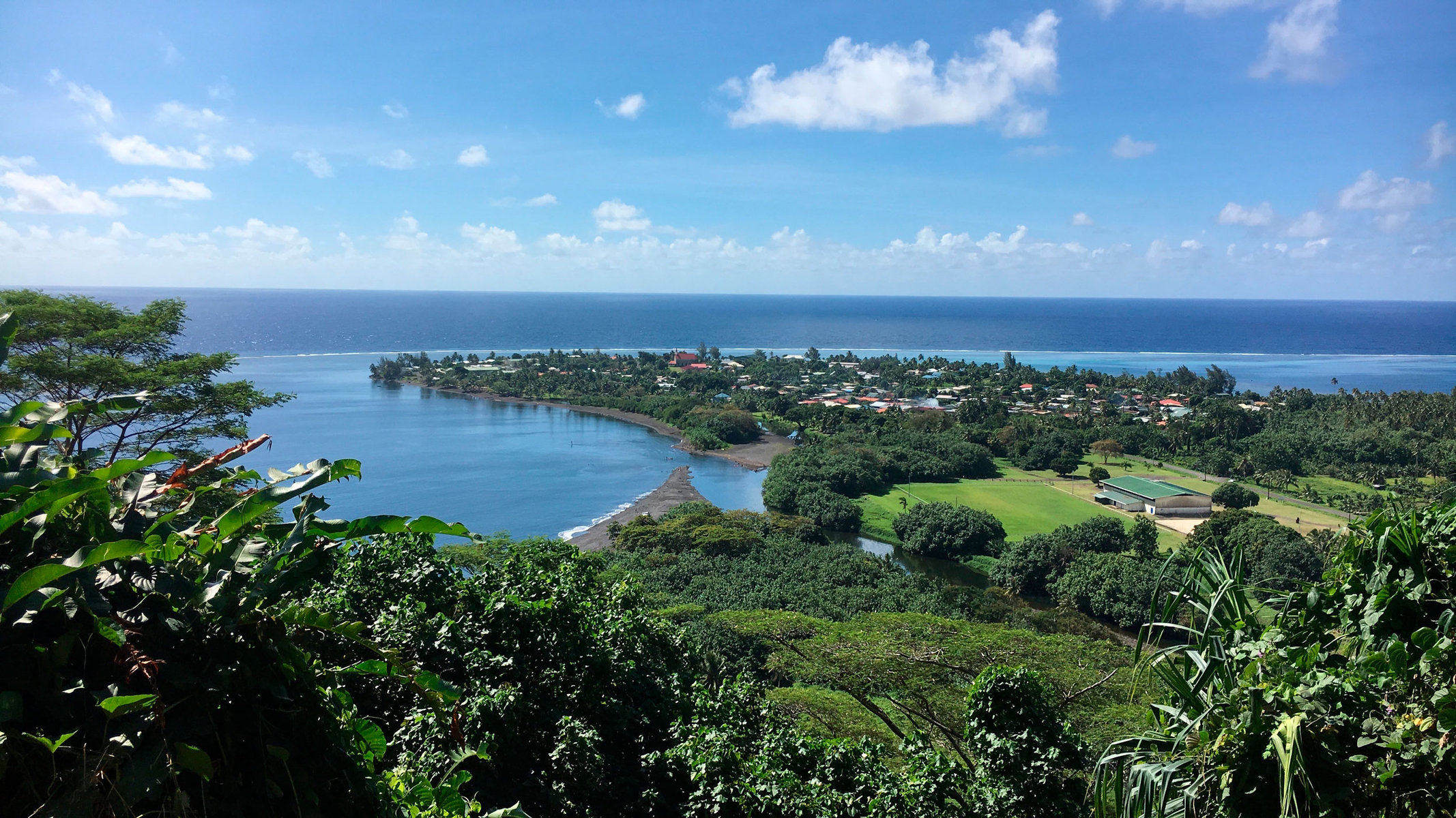 The village of Tautira, Tahiti, surrounded by trees and with ocean in the background.