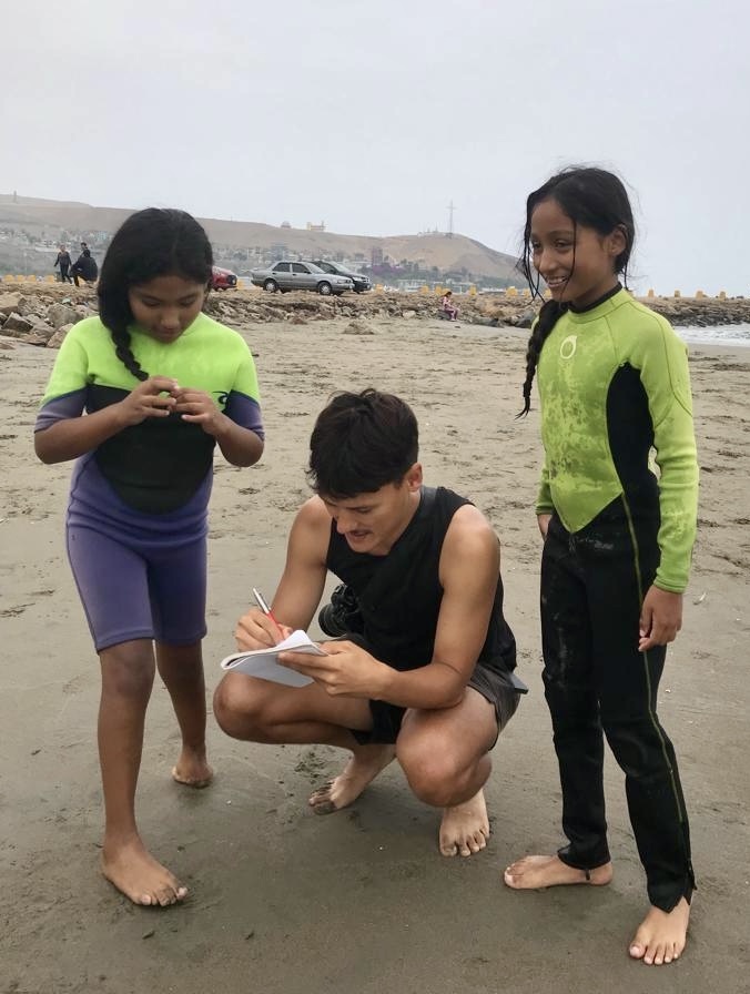 Journalist Peter Yeung talks with two children on a beach.