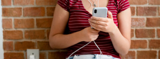 A teenager looking at her phone while it charges.