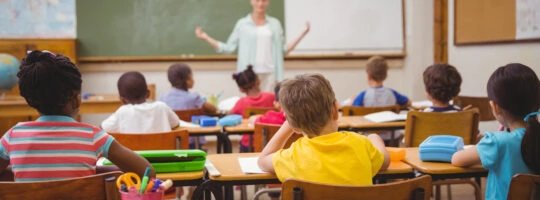 Students at desks listening to a teacher.