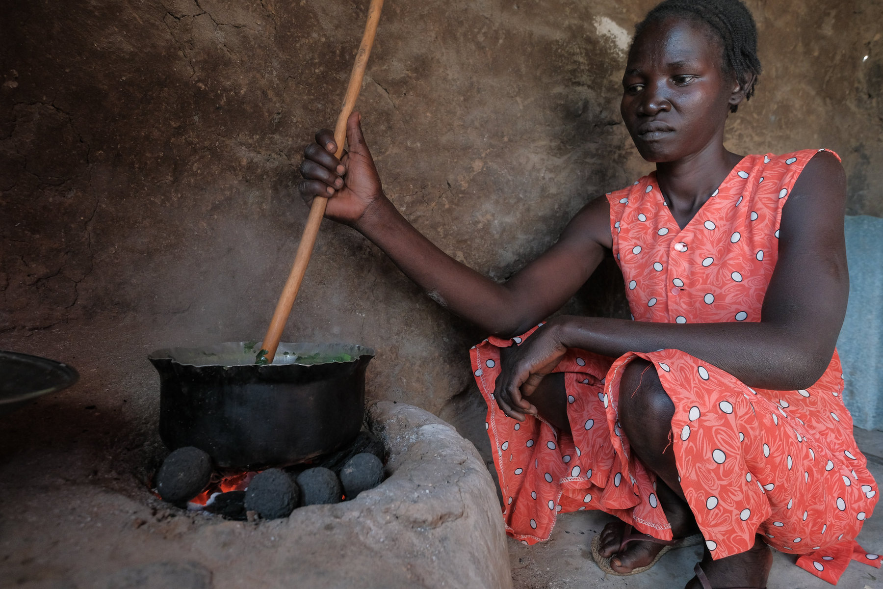 A woman cooking with charcoal.