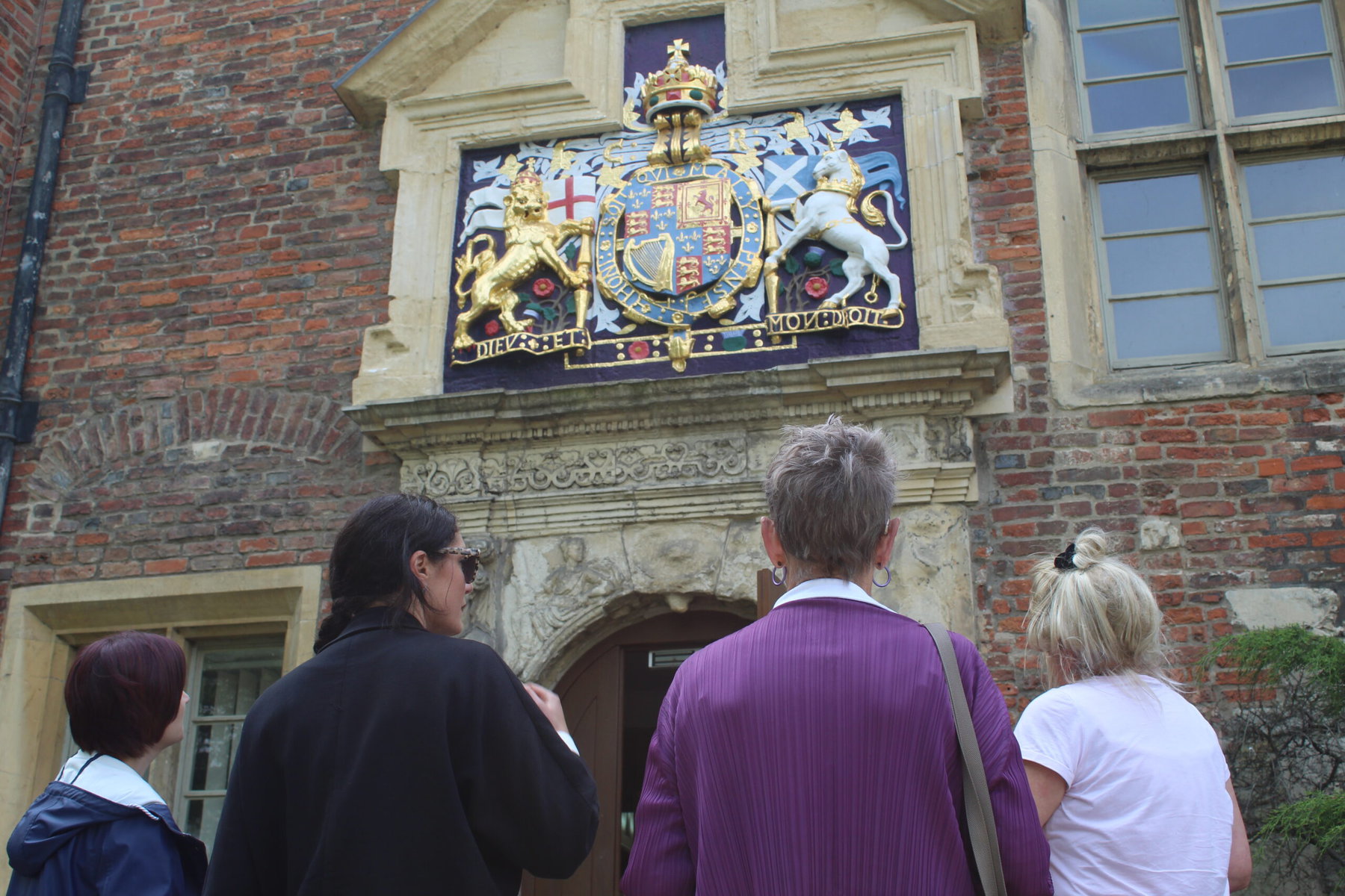 An Invisible Cities tour in York looks up at a coat of arms on a building.