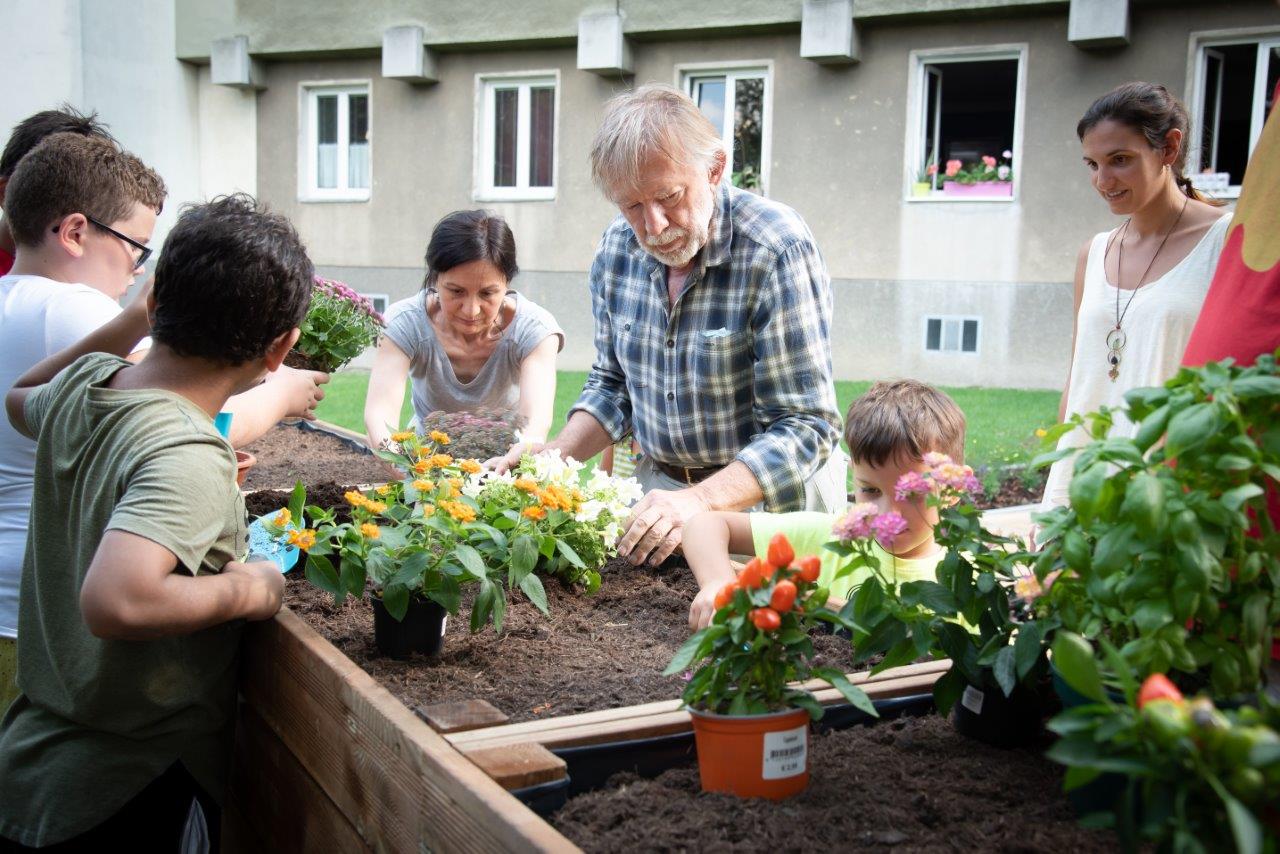 Seniors and children gardening together at the Hofferplatz intergenerational meeting point. 