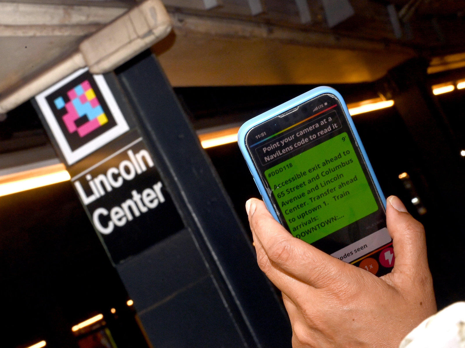 A phone using the NaviLens app is being held up to a NaviLens code at the Lincoln Center subway station.