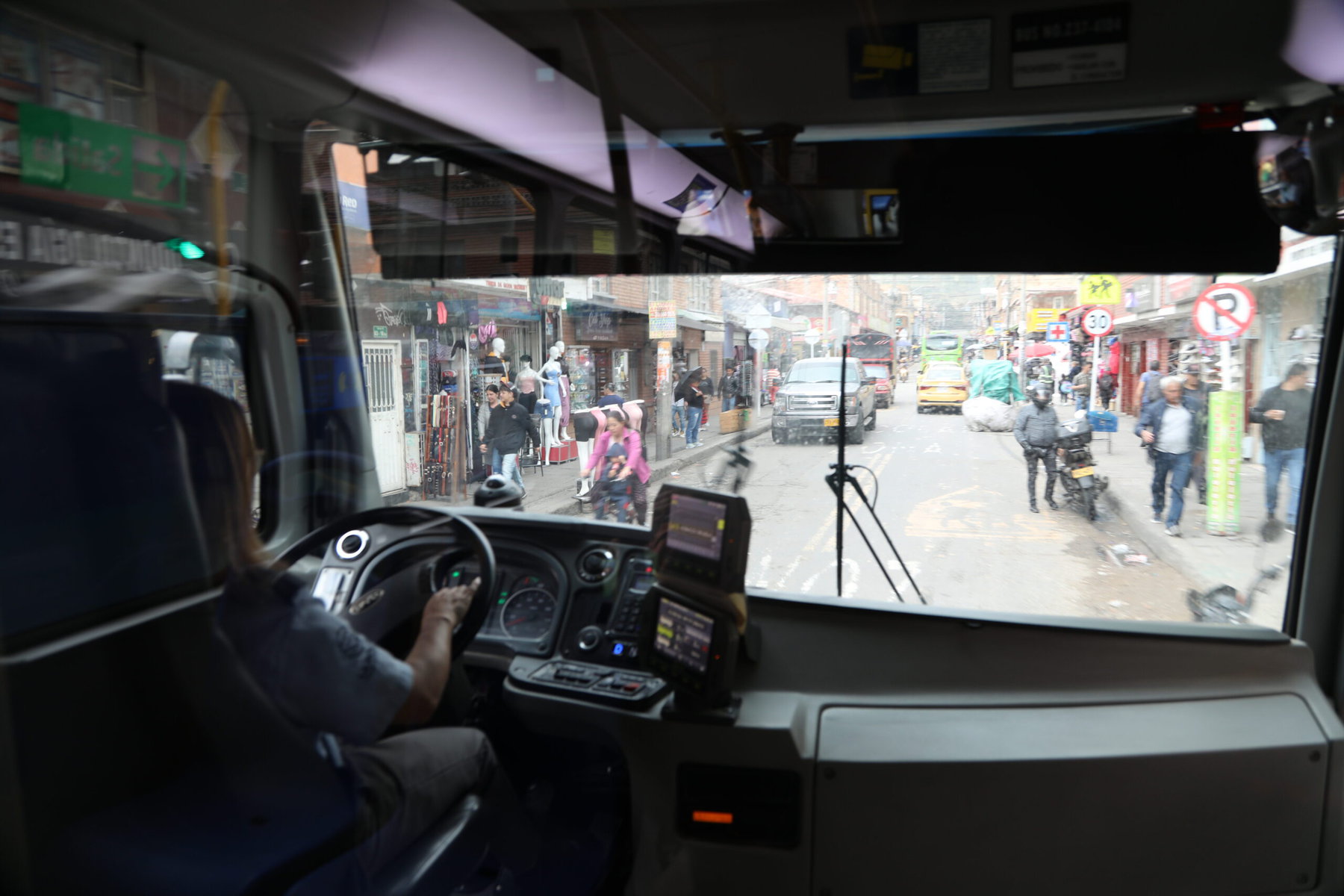 An inside view of a woman driving a bus.