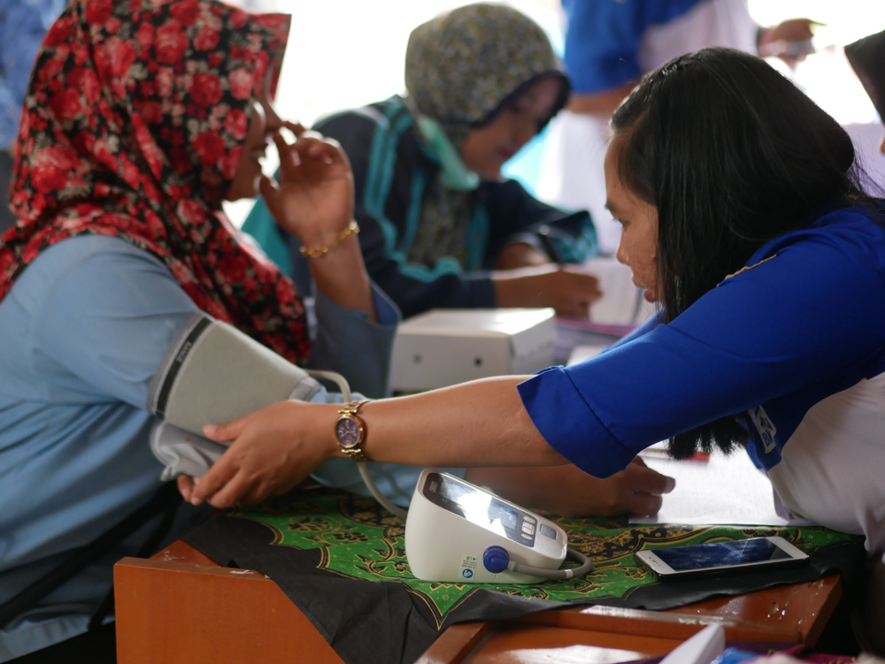 In Indonesia, a family planning field officer checks a patient's blood pressure before contraceptive implant insertion.