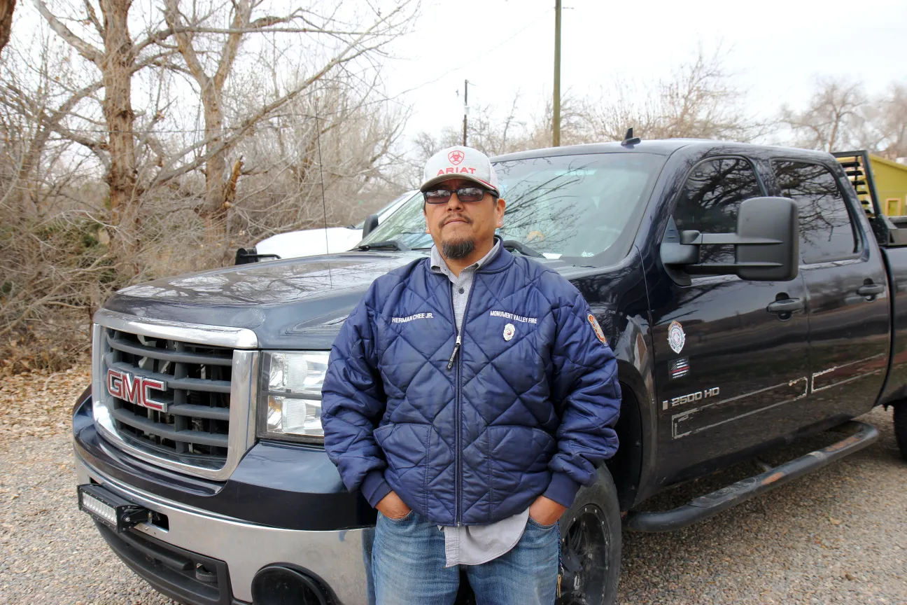 Herman Chee Jr., chief of the Monument Valley Fire Department, poses in front of a pickup truck.