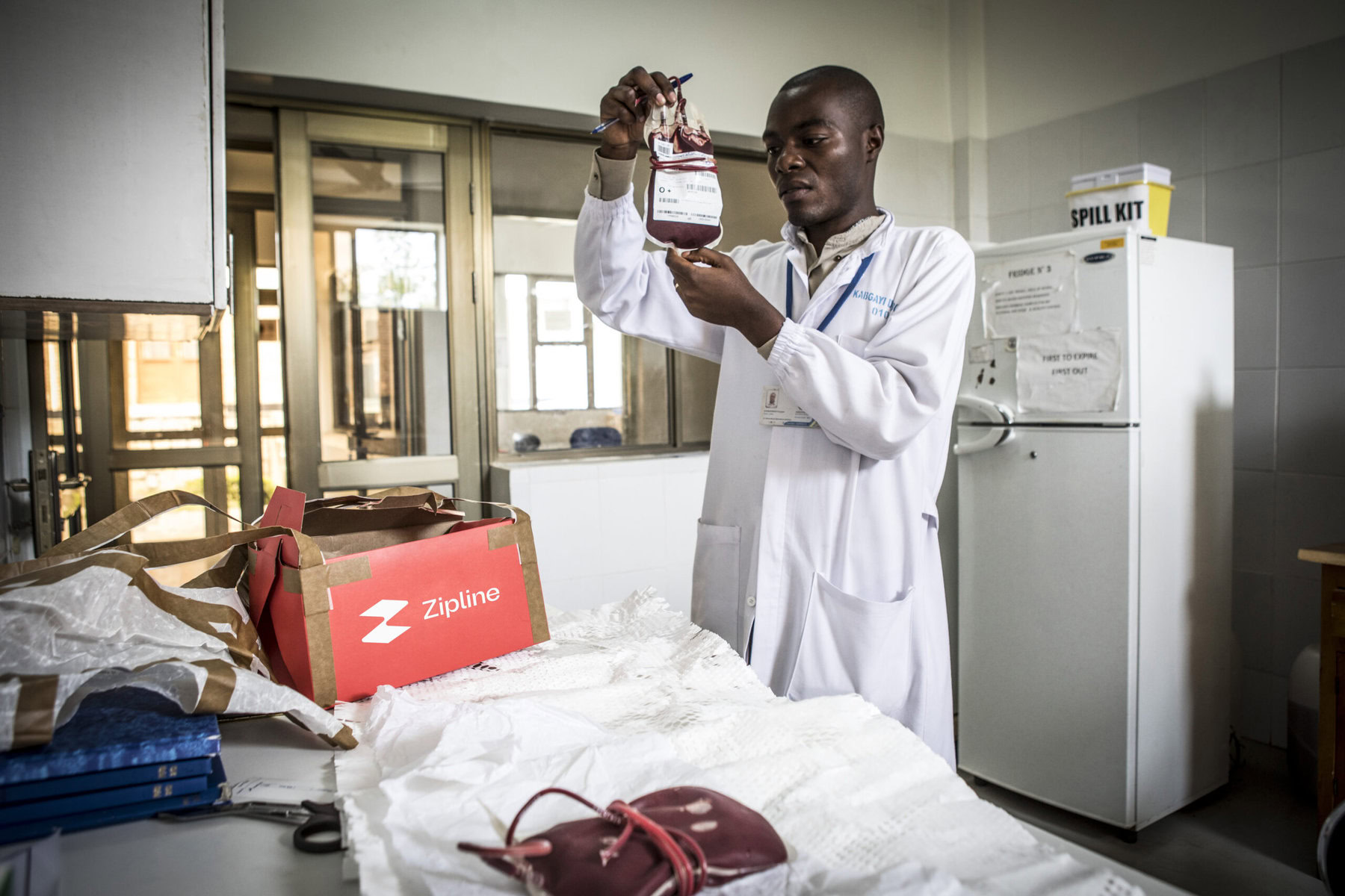 Kabgayi hospital lab technician Prosper Uzabariho inspects the blood sachet dropped in a cardboard box by paper parachute from the Zipline drone to the hospital.