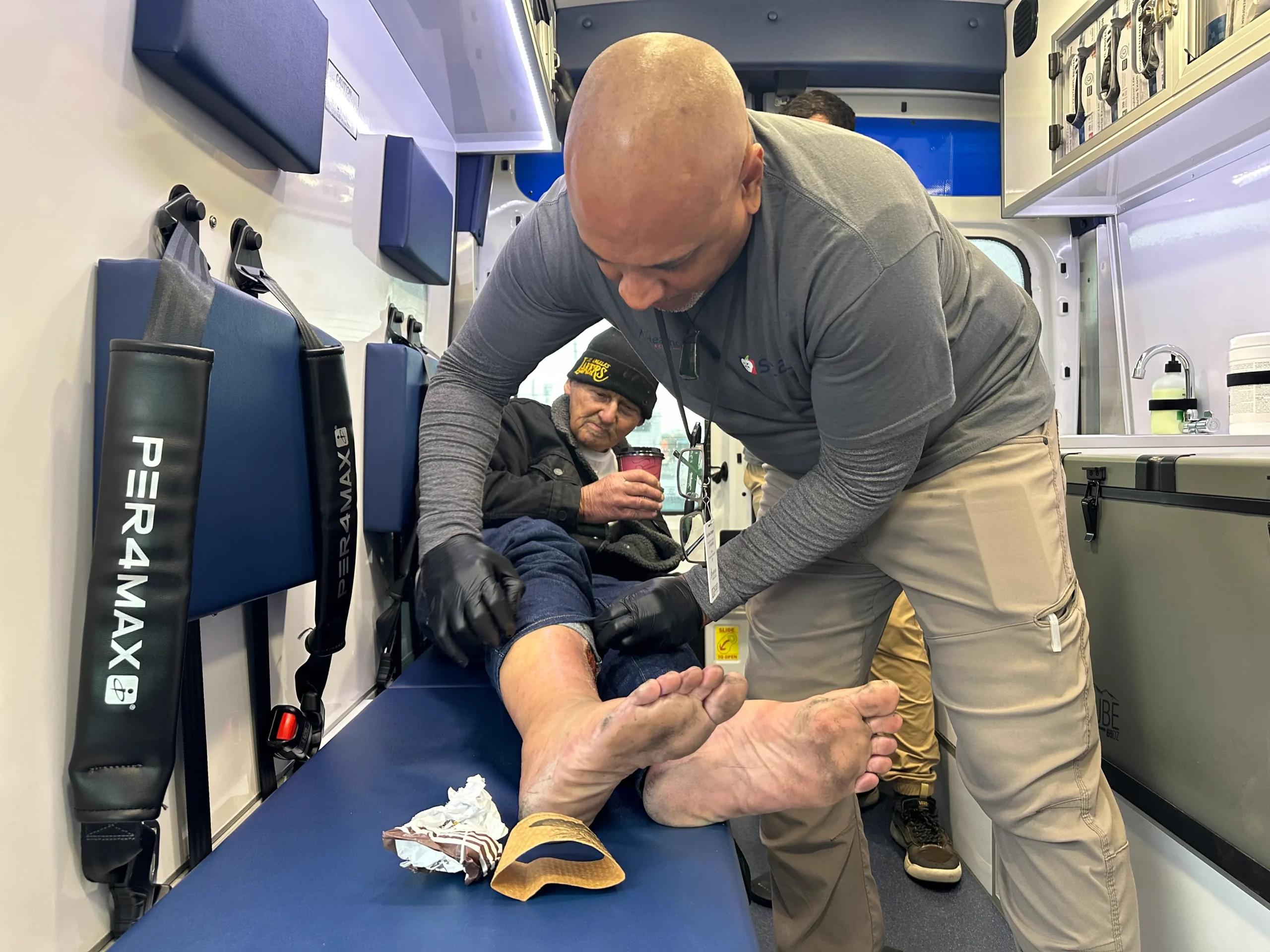 Physician assistant Daniel Speller, who works for a new nonprofit medical group called Healthcare in Action, treats a leg wound on Robert Smith, who is homeless in Long Beach, California.