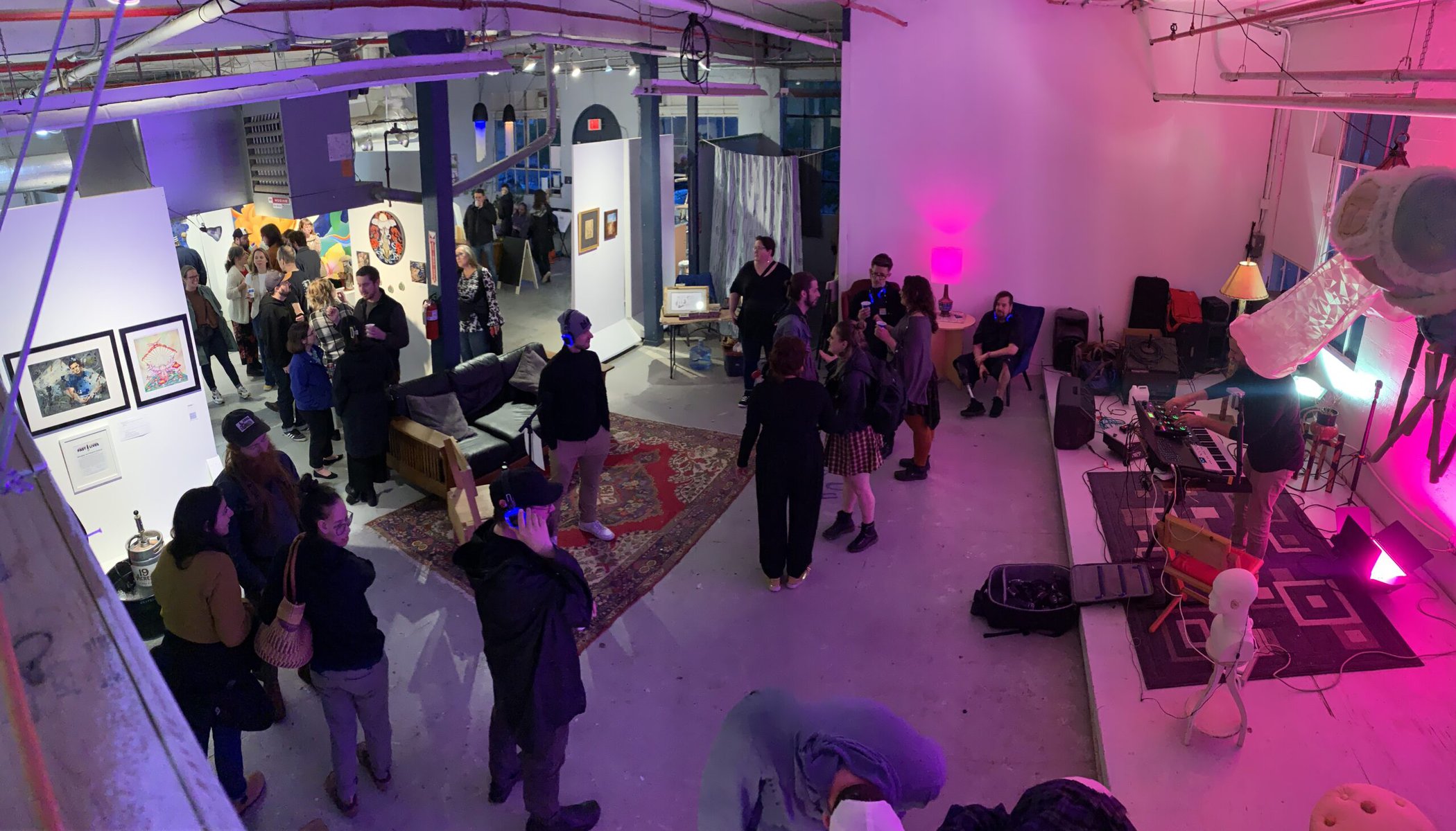 An evening arts event at Past Lives featuring pink and purple lighting.