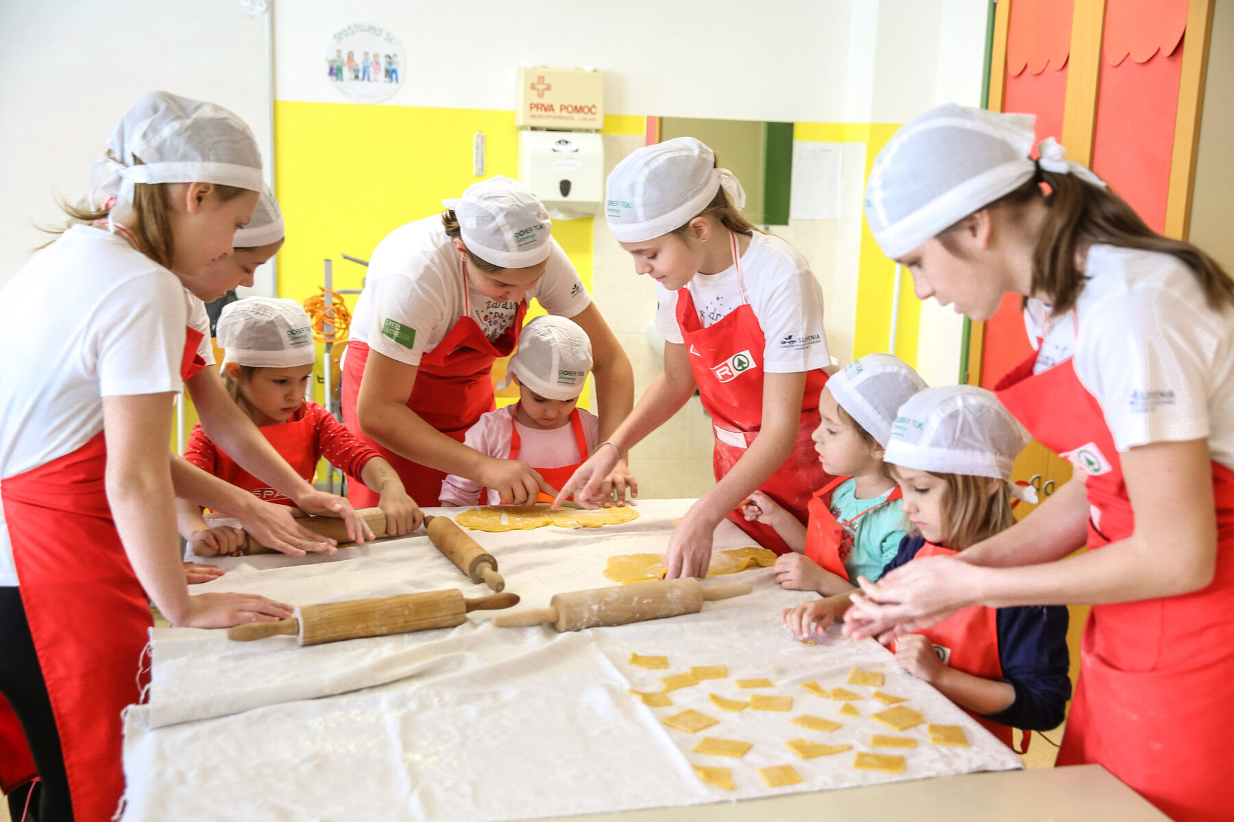 Young girls cook together with help from other girls.