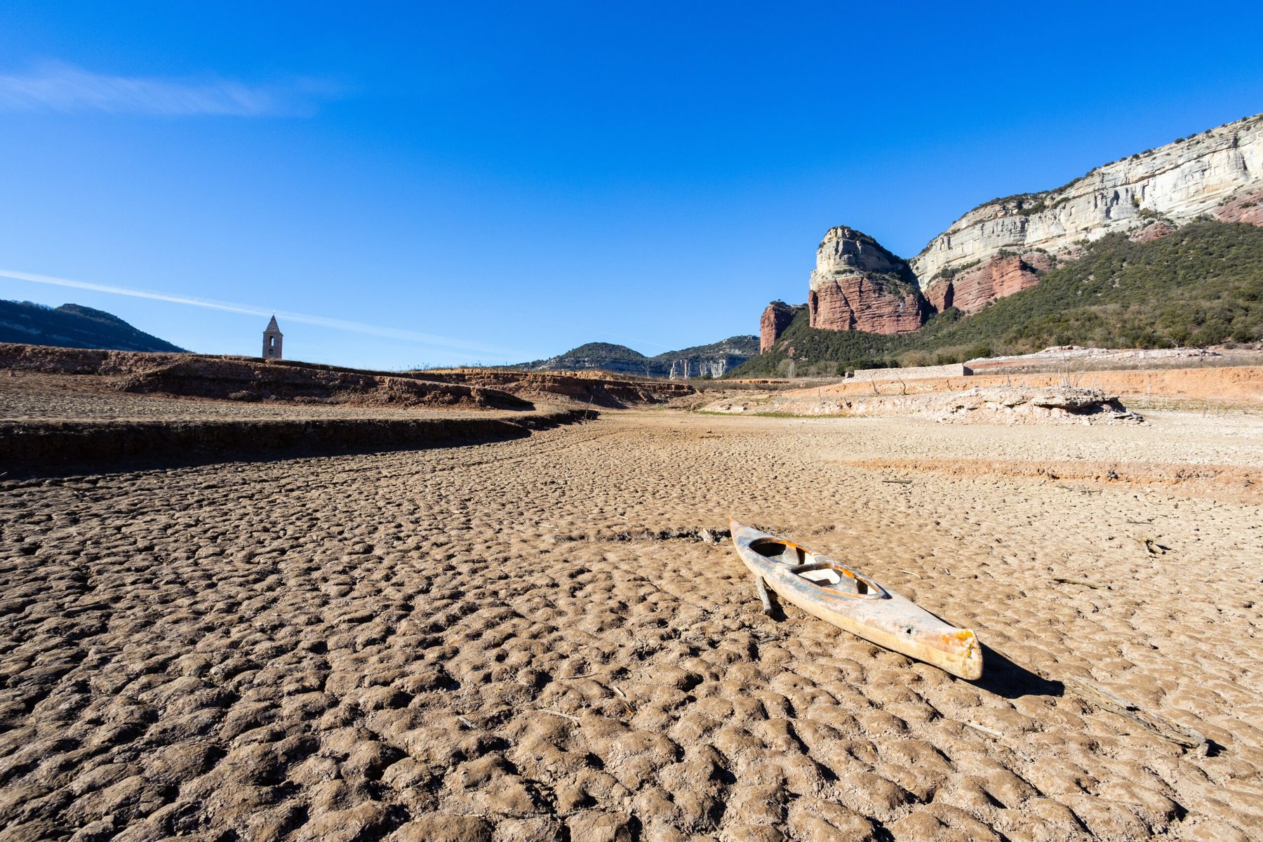 Low water levels in Barcelona's Sau Reservoir in February 2024. A kayak sits on sand instead of water.