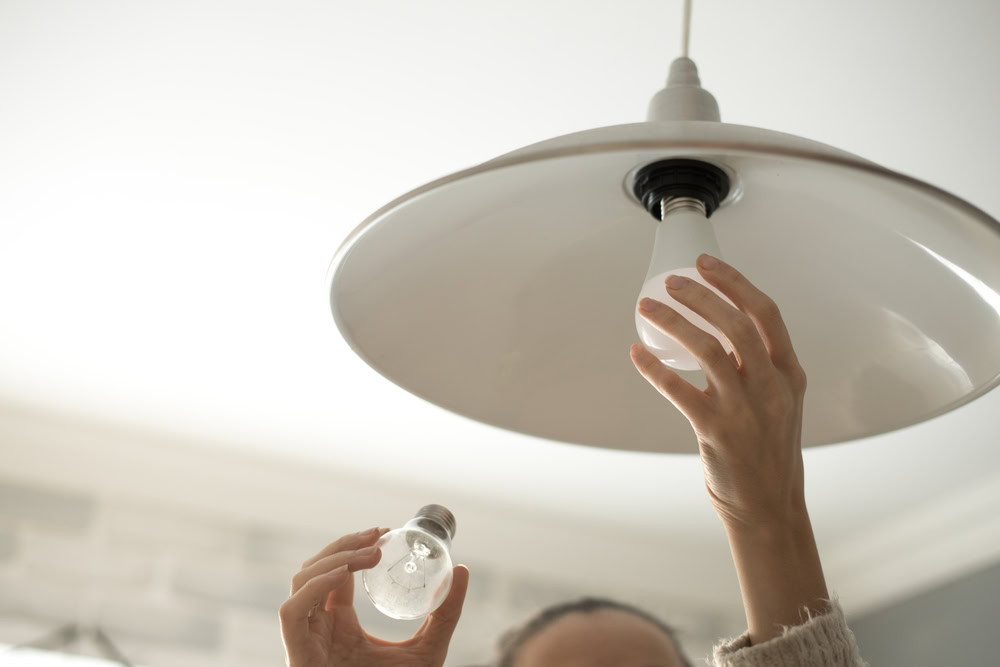 A woman changing a lightbulb.