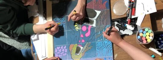 People collaborate on a colorful piece of art.