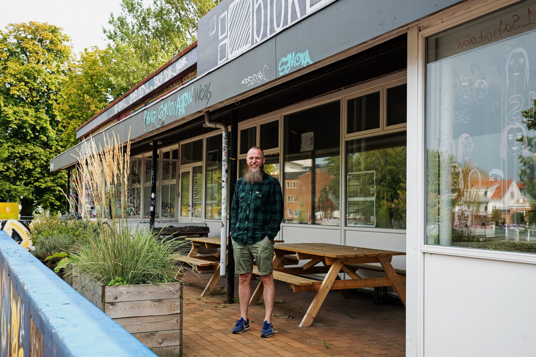 Mikael Odder Nielsen stands outside a storefront with picnic tables.