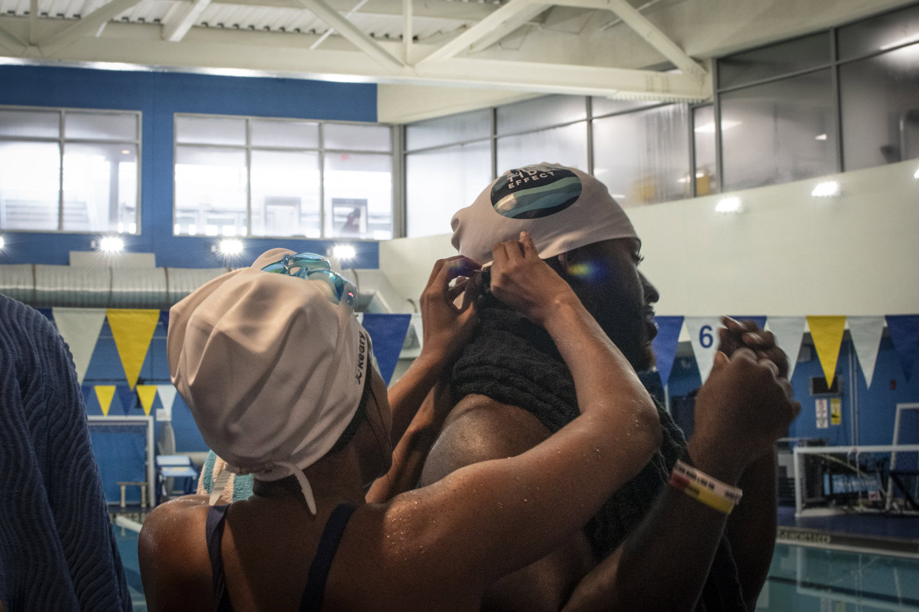 Participants of the NYCHA Swim Corps program help each other to put on their swimming caps.