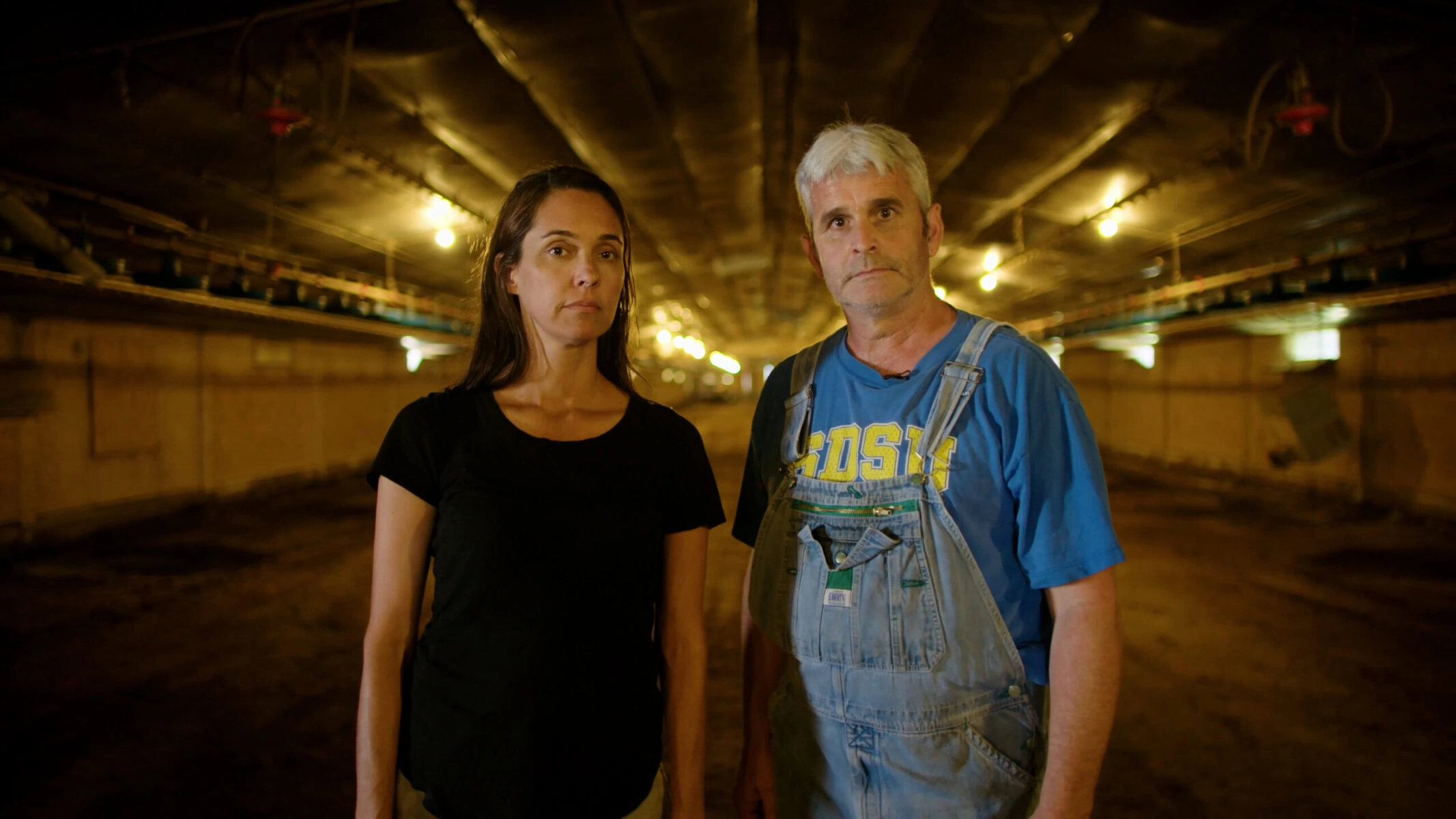 Leah Garcés and Craig Watts pose in a structure that was formerly used to factory farm chickens.