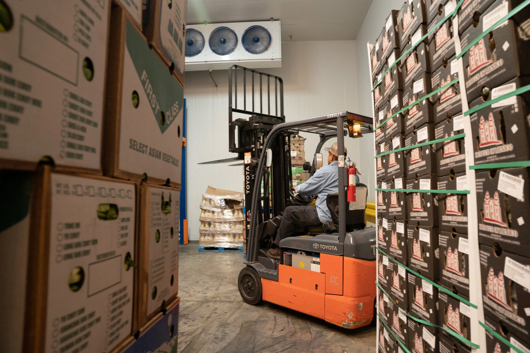 A worker drives a forklift between aisles of boxes in the Food Forward warehouse.